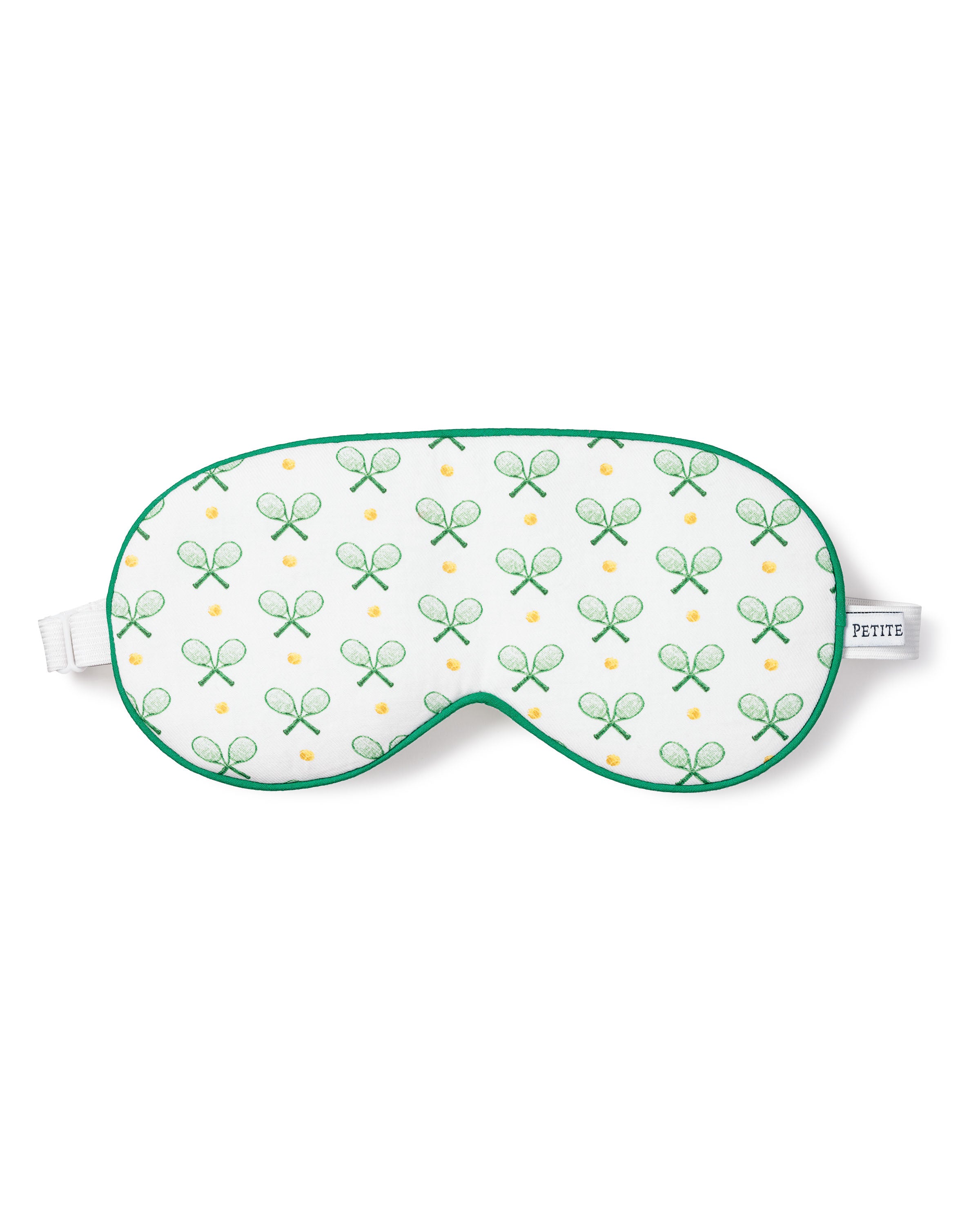 The Petite Plume Adults Sleep Mask in Match Point showcases a tennis print with green rackets and yellow balls, complete with green trim and an adjustable white strap. Pair it with matching pajamas for a chic set. The brand label adds a touch of elegance to the side.