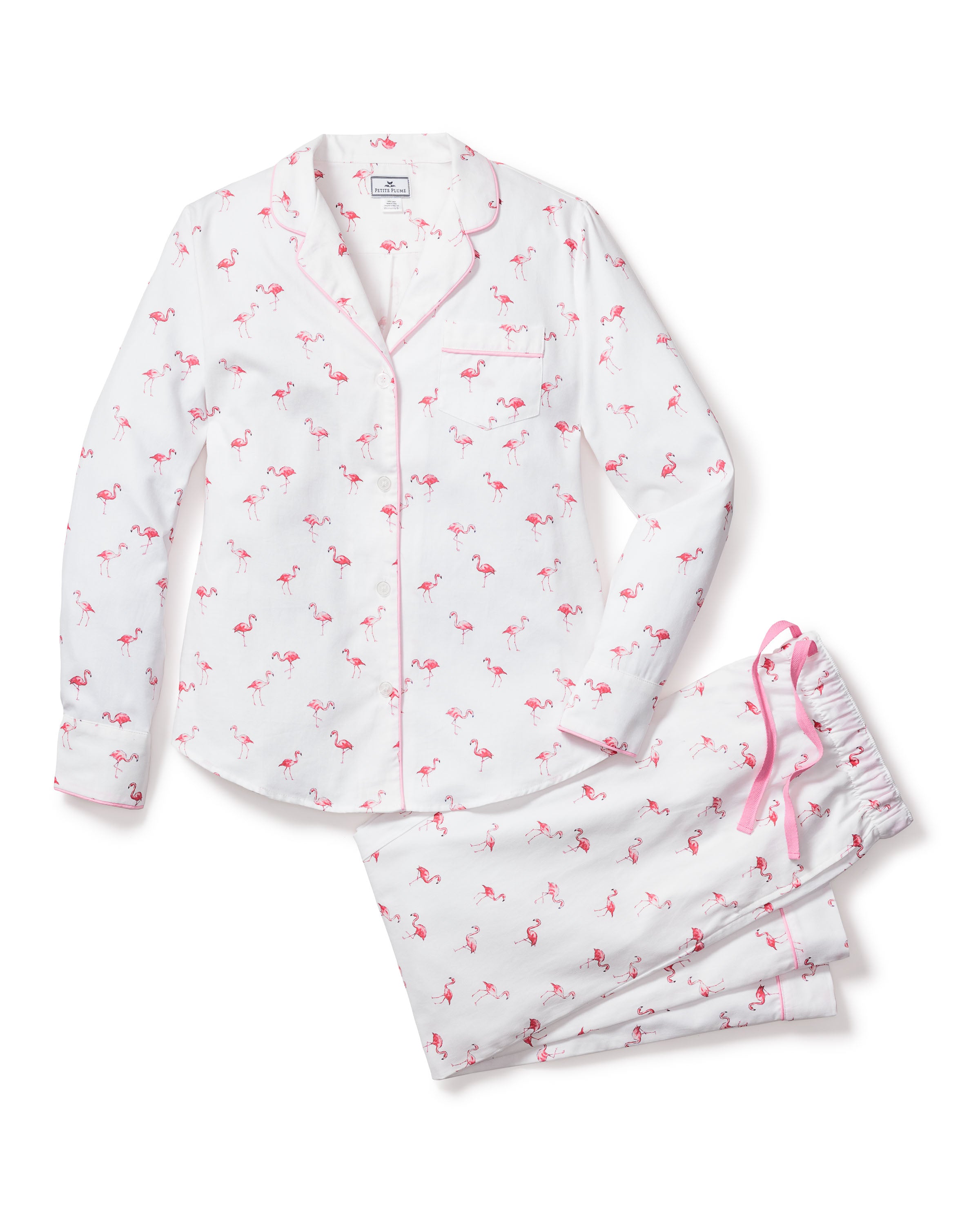 The Womens Twill Pajama Set in Flamingos by Petite Plume features a tropical pink flamingo pattern. It includes a long-sleeve button-up shirt with a front pocket and pants, both with pink piping. The pants are designed for comfort with a pink drawstring.