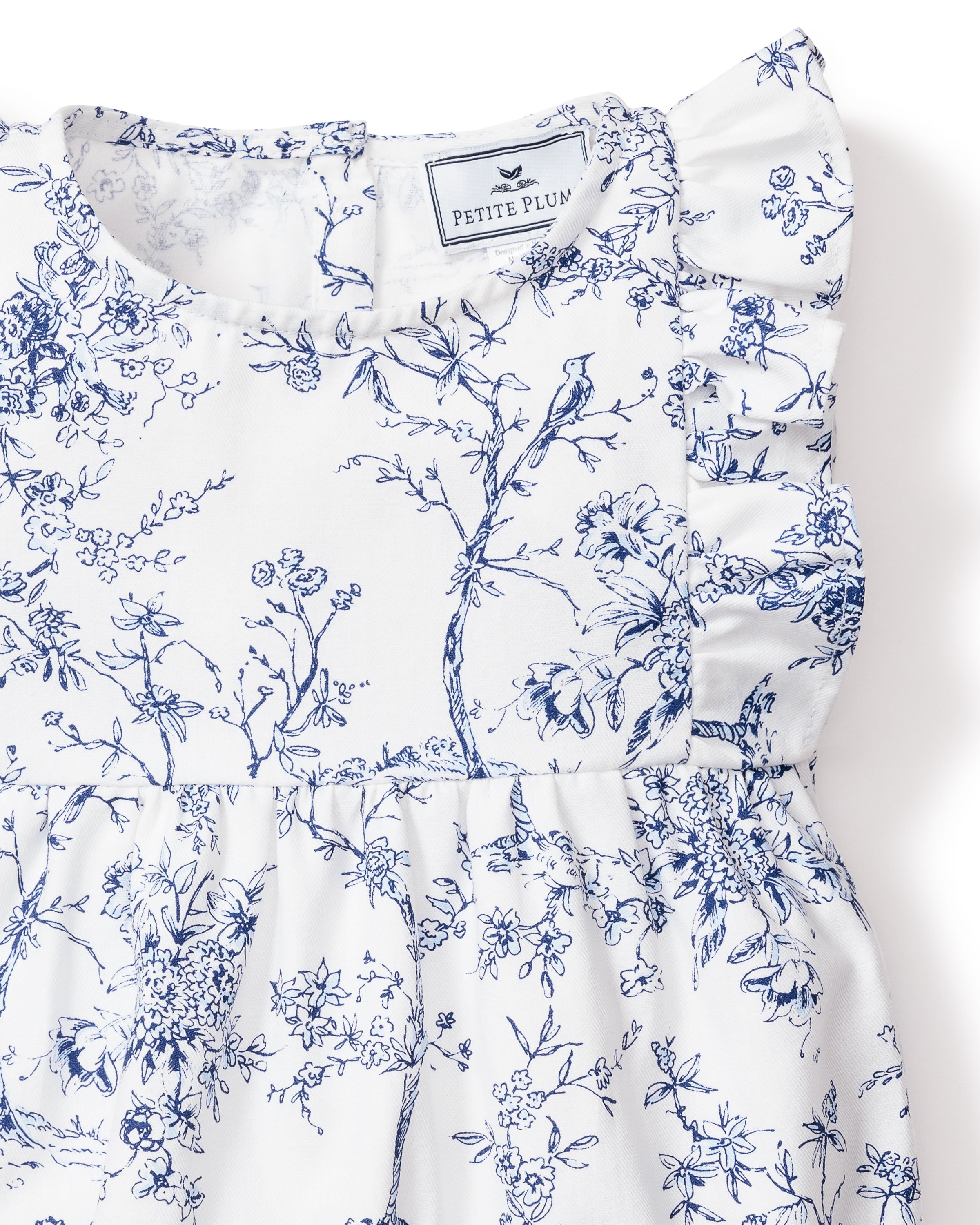 Close-up of the Babys Twill Ruffled Romper in Timeless Toile by Petite Plume, featuring intricate blue floral patterns on white fabric with a ruffled shoulder detail reminiscent of the Victorian era.