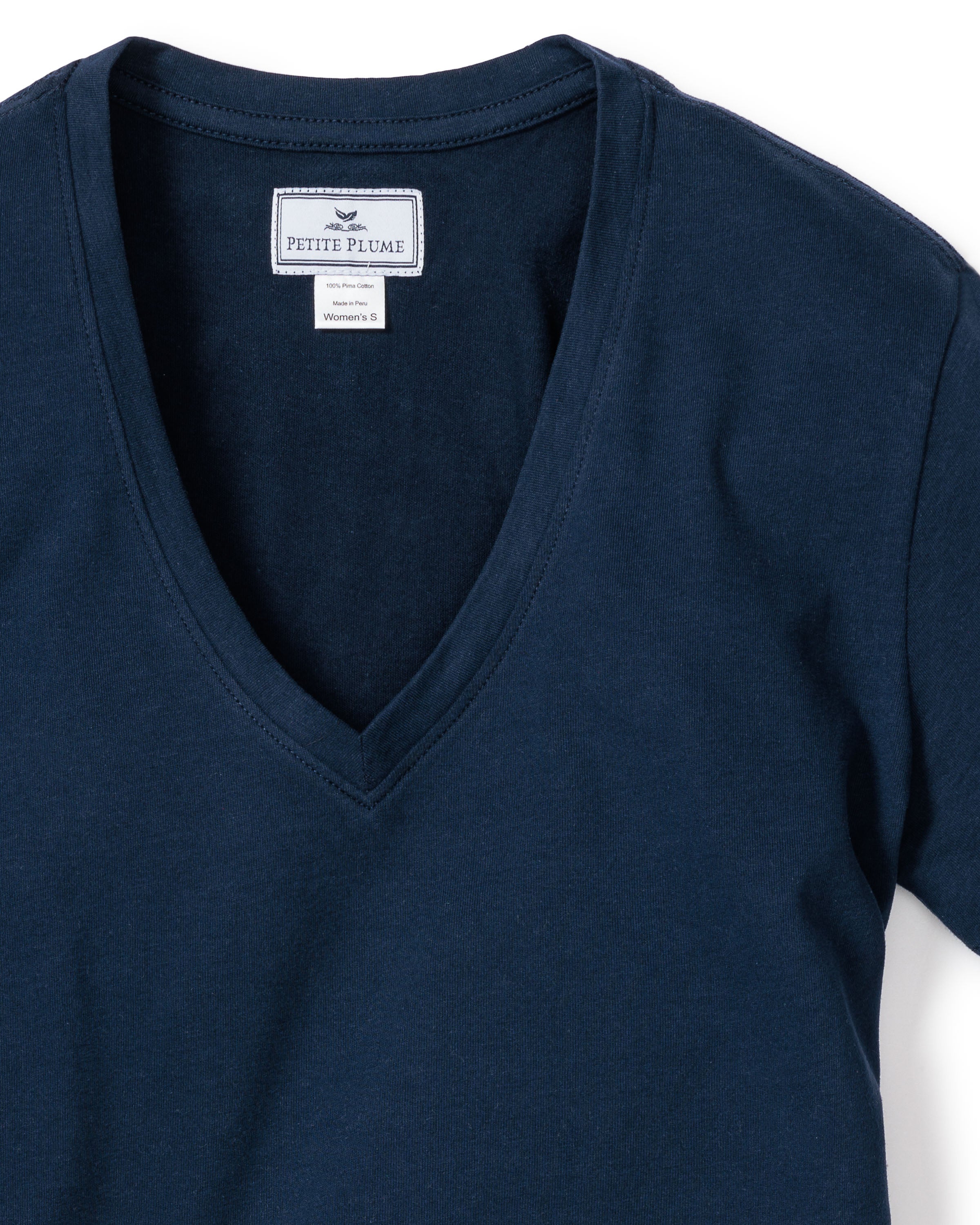 Close-up of Womens Pima Short Sleeve Top in Navy by Petite Plume, showcasing a soft jersey knit with care instructions at the neckline. The Pima cotton fabric is laid out smoothly on a white background.