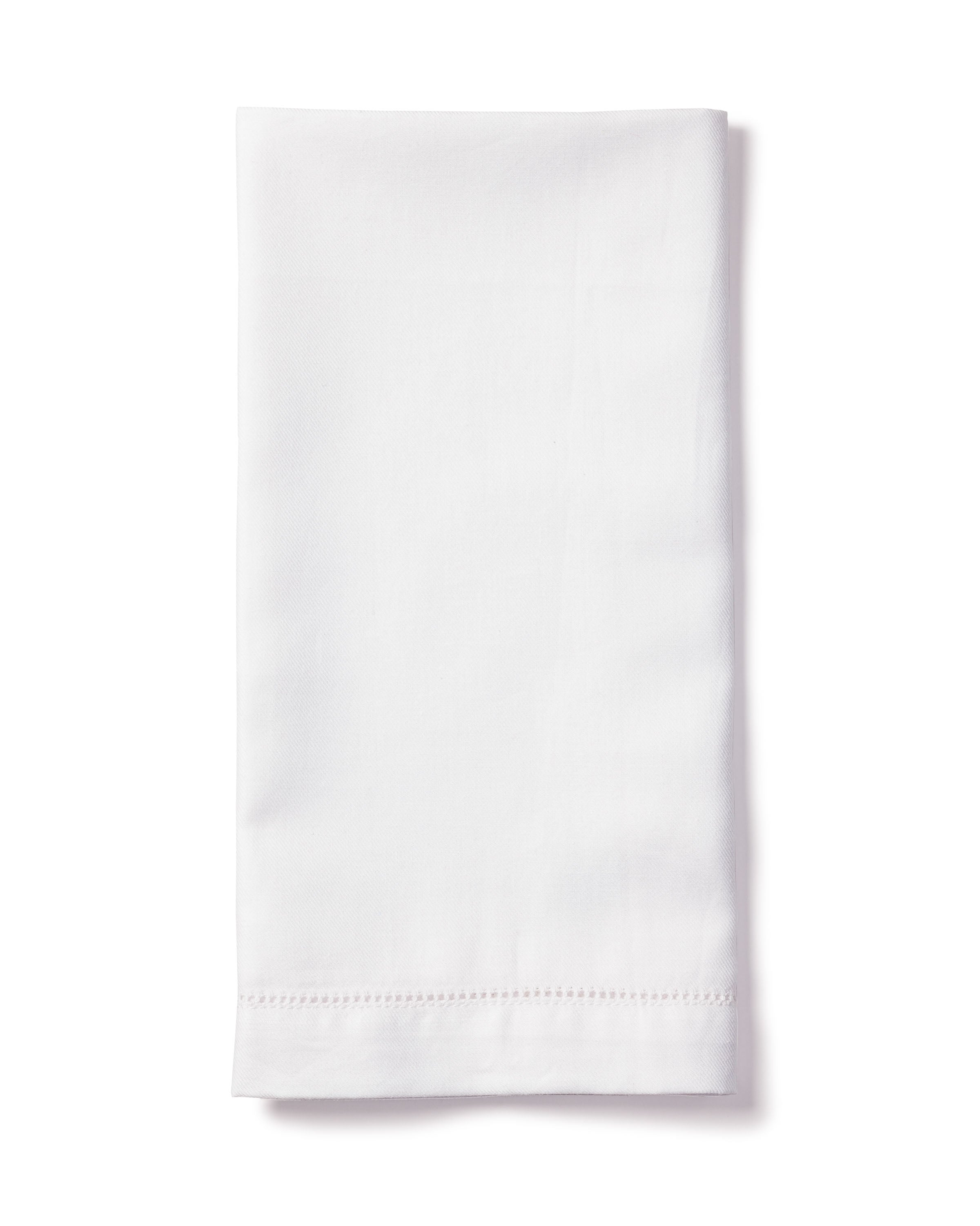 A neatly folded Signature Twill Napkin in White from Petite Plume rests against a white background. Made of 100% cotton, its perfect for enhancing a festive tablescape and features a simple hemmed edge.