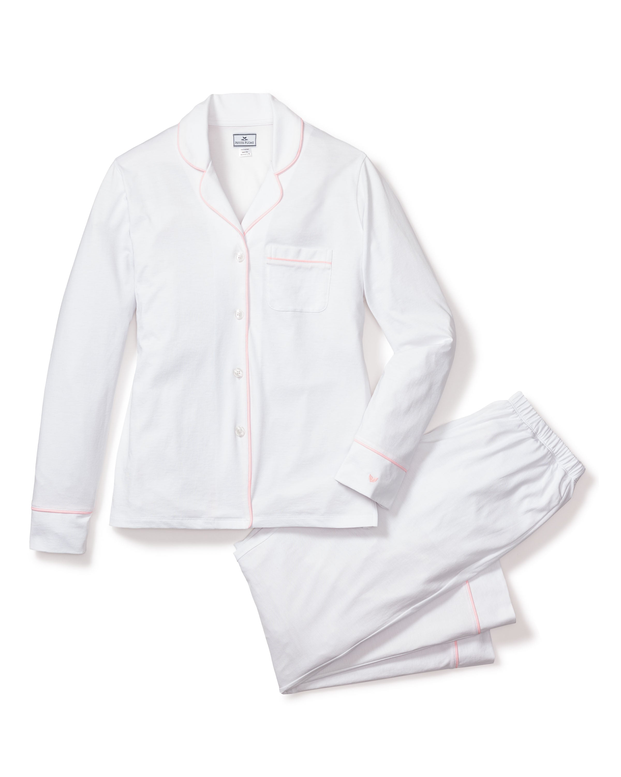 The Womens Pima Pajama Set by Petite Plume, crafted from luxury Peruvian Pima cotton, includes a white long-sleeve button-up top with collar and pink piping, plus pants with an elastic waistband. Elegantly laid flat on a white background, this set exudes sophistication and comfort.