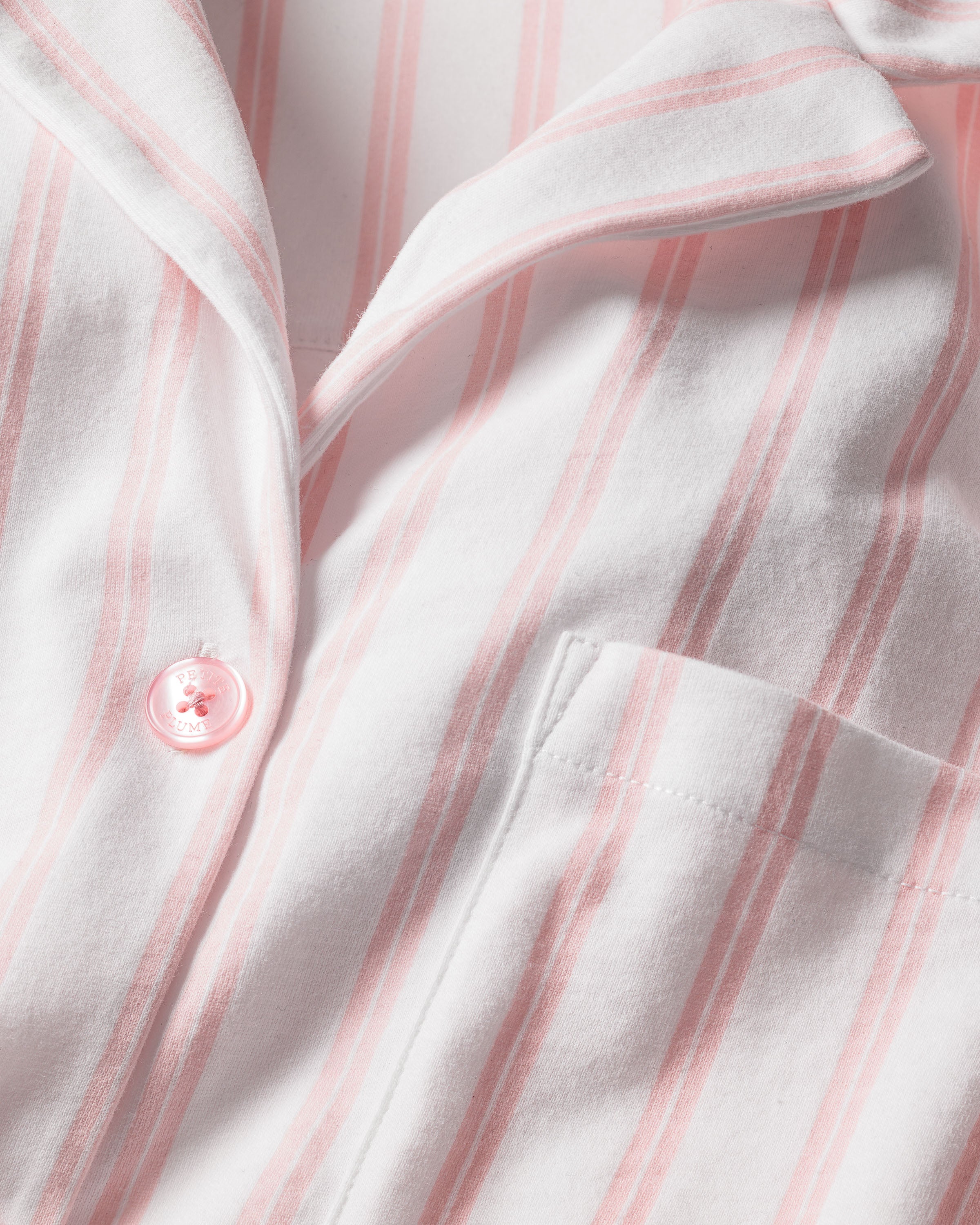 Close-up of the luxurious Petite Plume Olivia Wide Leg Pima Pajama Set in Pink Stripe, showcasing its soft Peruvian Pima cotton fabric, elegant vertical stripes, visible pocket, and pink button, highlighting its exceptional texture and design.