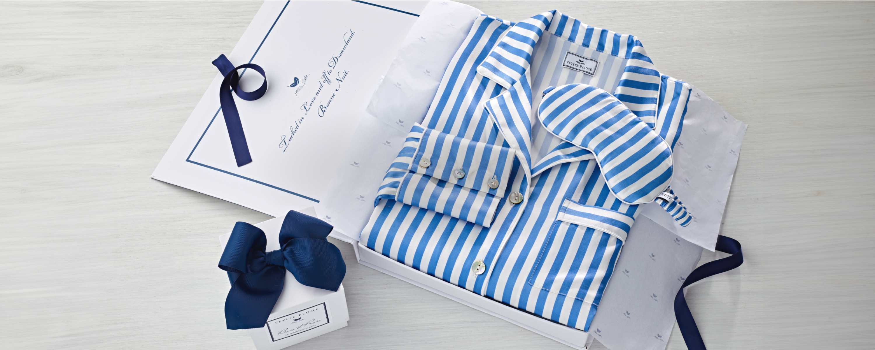 Women's silk blue and white stripe pajama set with matching sleep mask in a gift box. Smaller gift box with navy ribbon