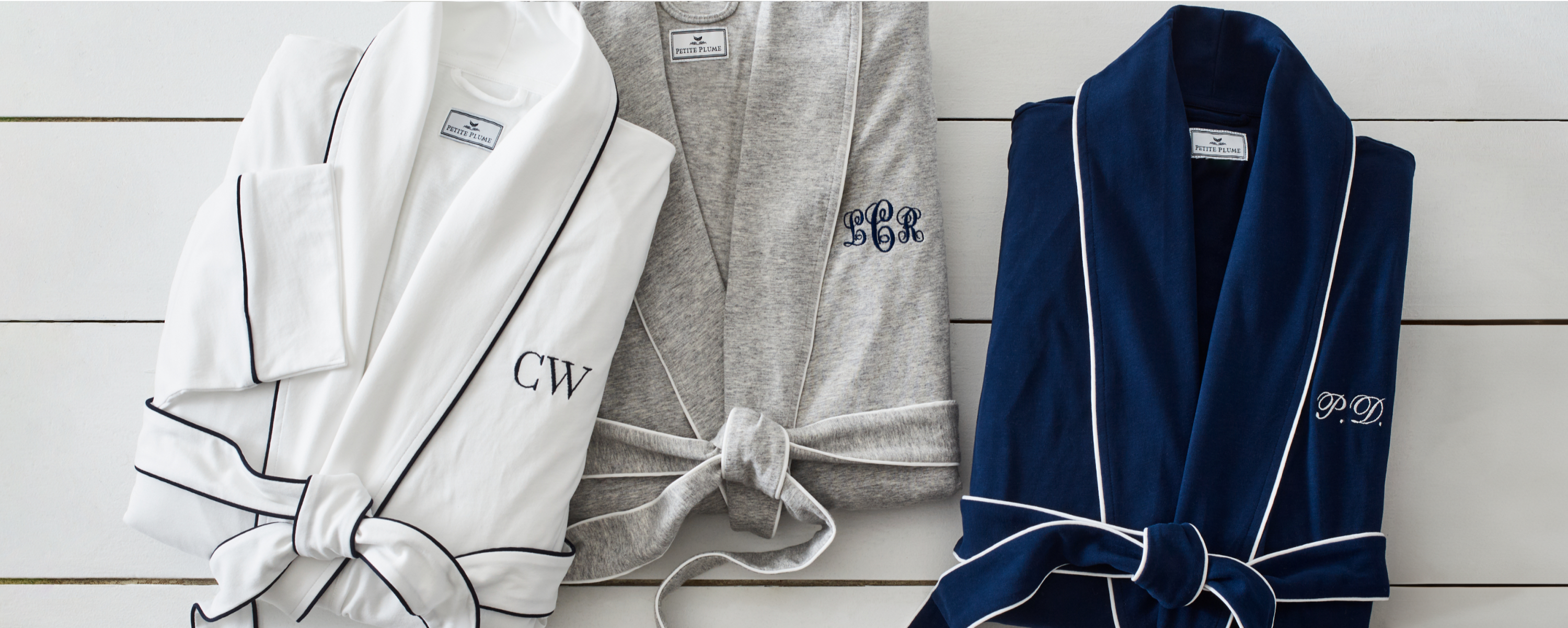 Group image of 3 robes in white, grey and navy. Each robe has initials monogrammed on the right side of the robe