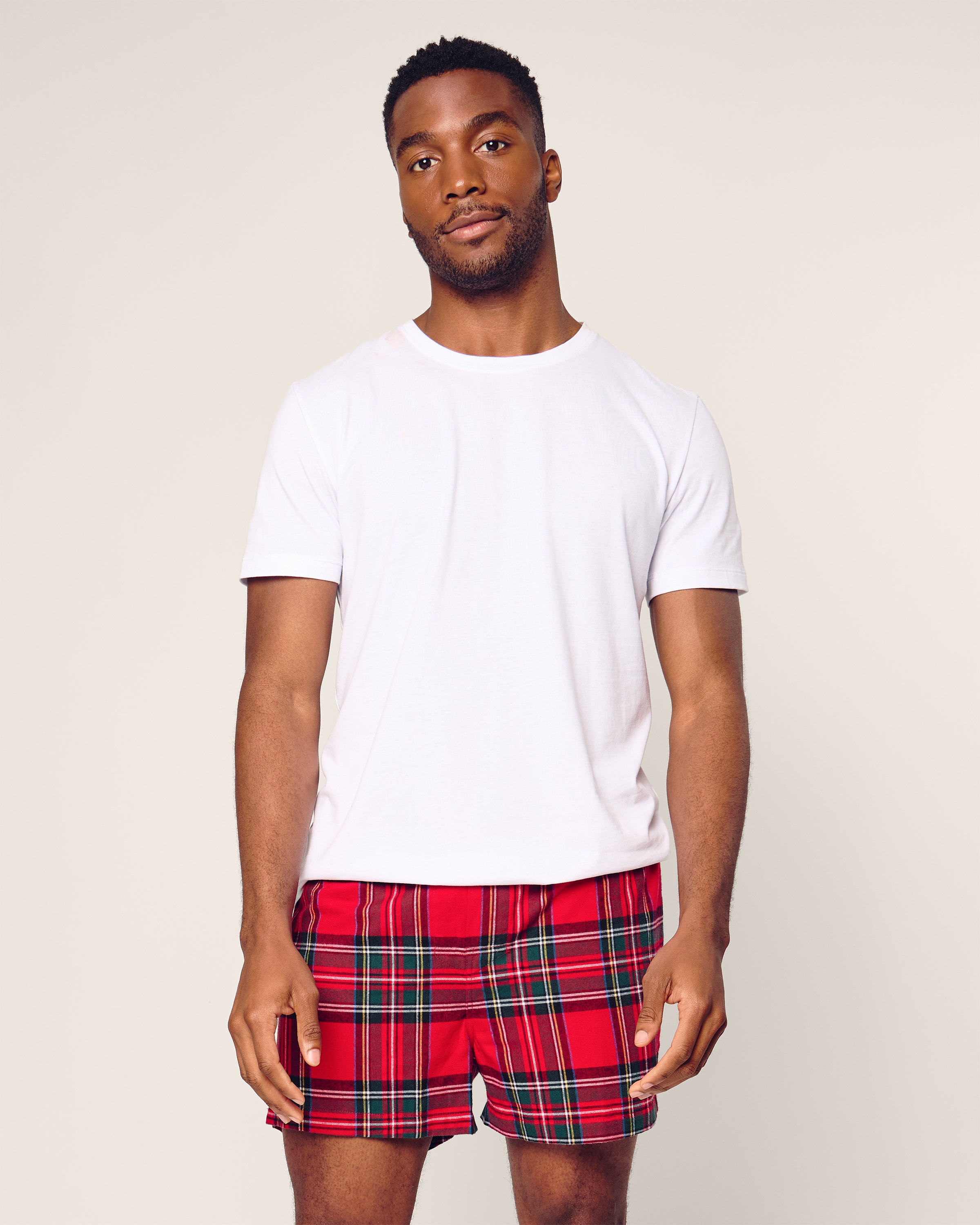 A man wearing Petite Plumes Mens Twill Boxers in Holiday Red, made from woven cotton twill, stands against a plain background.