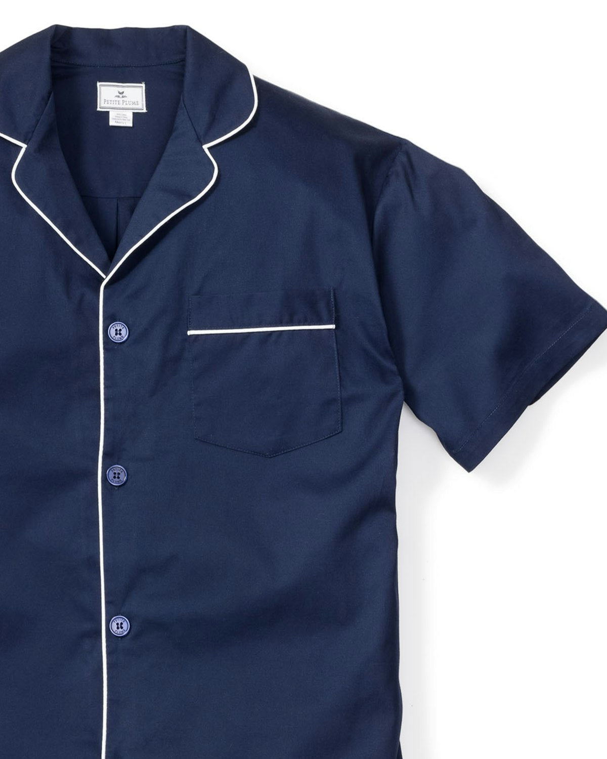 The Mens Twill Pajama Short Set in Navy by Petite Plume is a classic luxury piece featuring a navy short-sleeve top with white buttons, piping, collar, and left chest pocket. Made from 100% cotton, it combines comfort and style for a restful night.