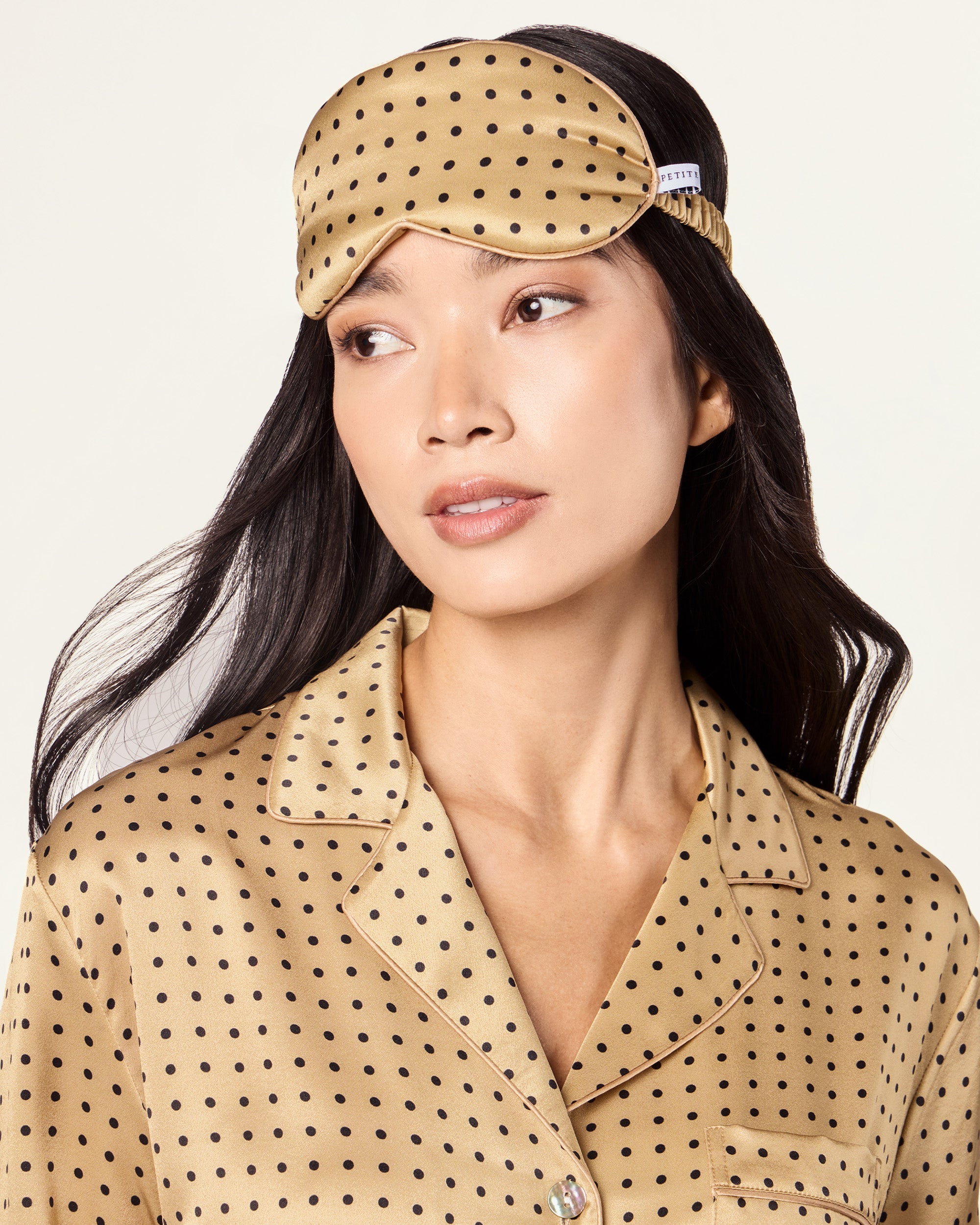 The Adult's Silk Sleep Mask in Gold with Black Polka Dots features an elastic strap and is shown on a white background.