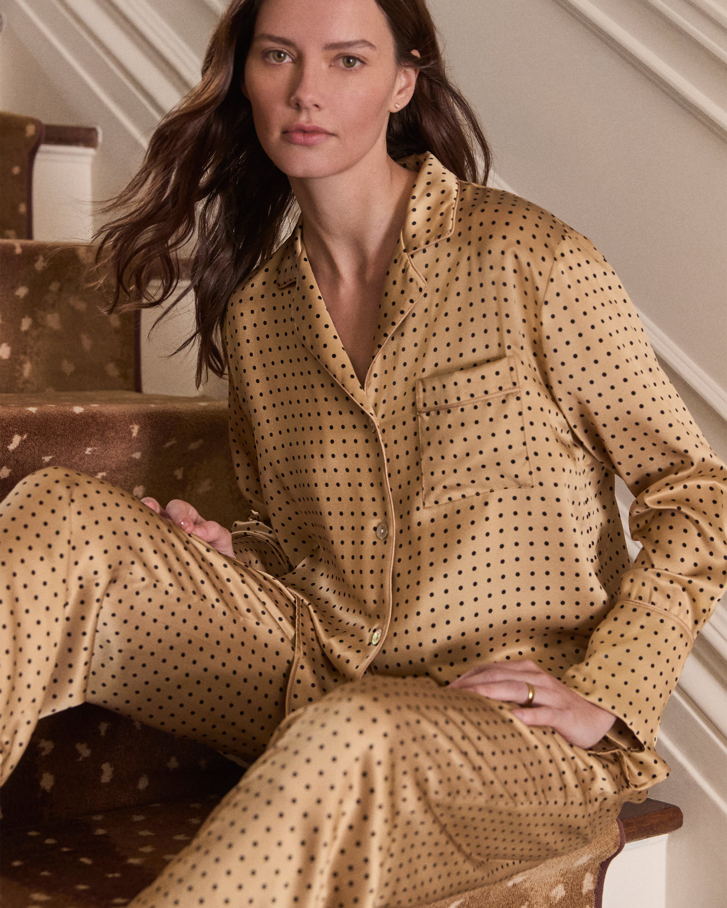 The Women's Silk Pajama Set features a gold fabric with black polka dots, including a long-sleeve button-up top with chest pocket and matching drawstring pants.