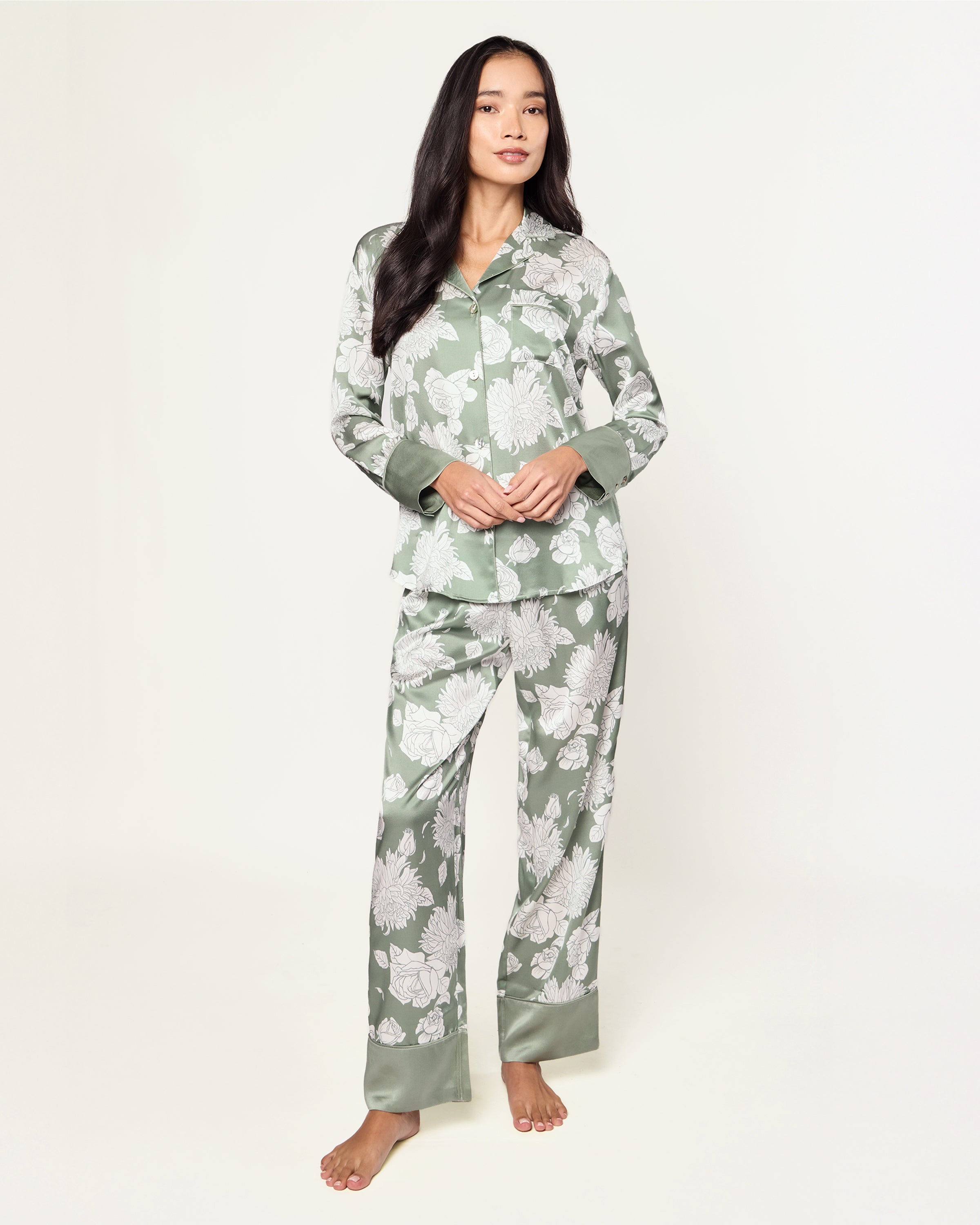 Women's Silk Pajama Set in Sage Bloom: a sage green satin set with a white floral pattern, featuring a long-sleeve button-up top with chest pocket and matching drawstring pants.