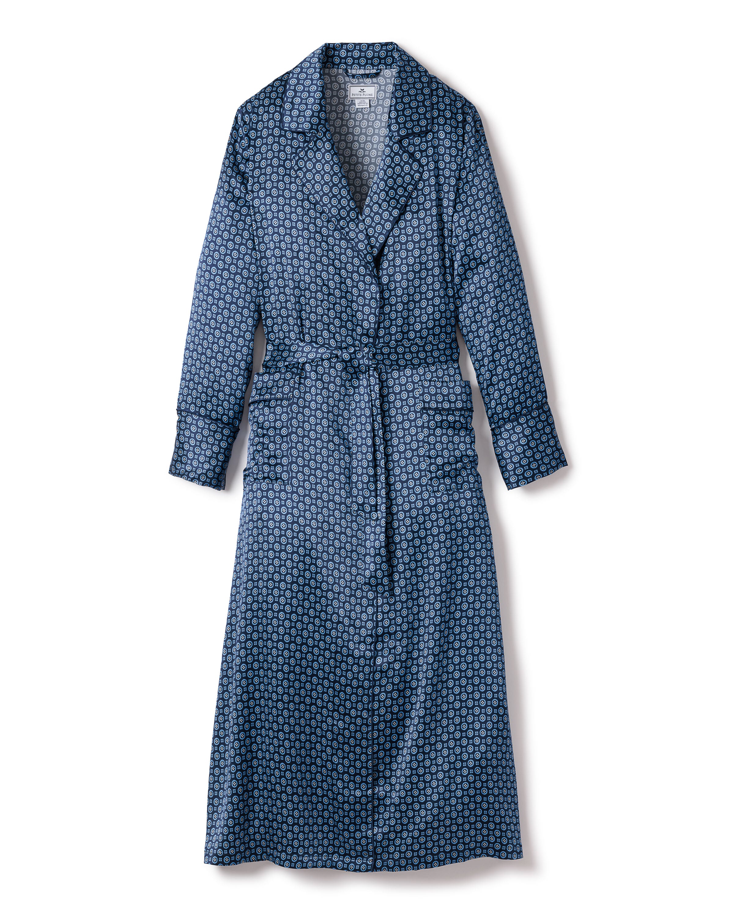 The Womens Silk Robe in Midnight Foulard by Petite Plume is crafted from luxurious mulberry silk and features a geometric pattern in blue. It includes a collar, long sleeves, and a matching fabric belt, offering soft, hypoallergenic comfort ideal for lounging or casual wear.