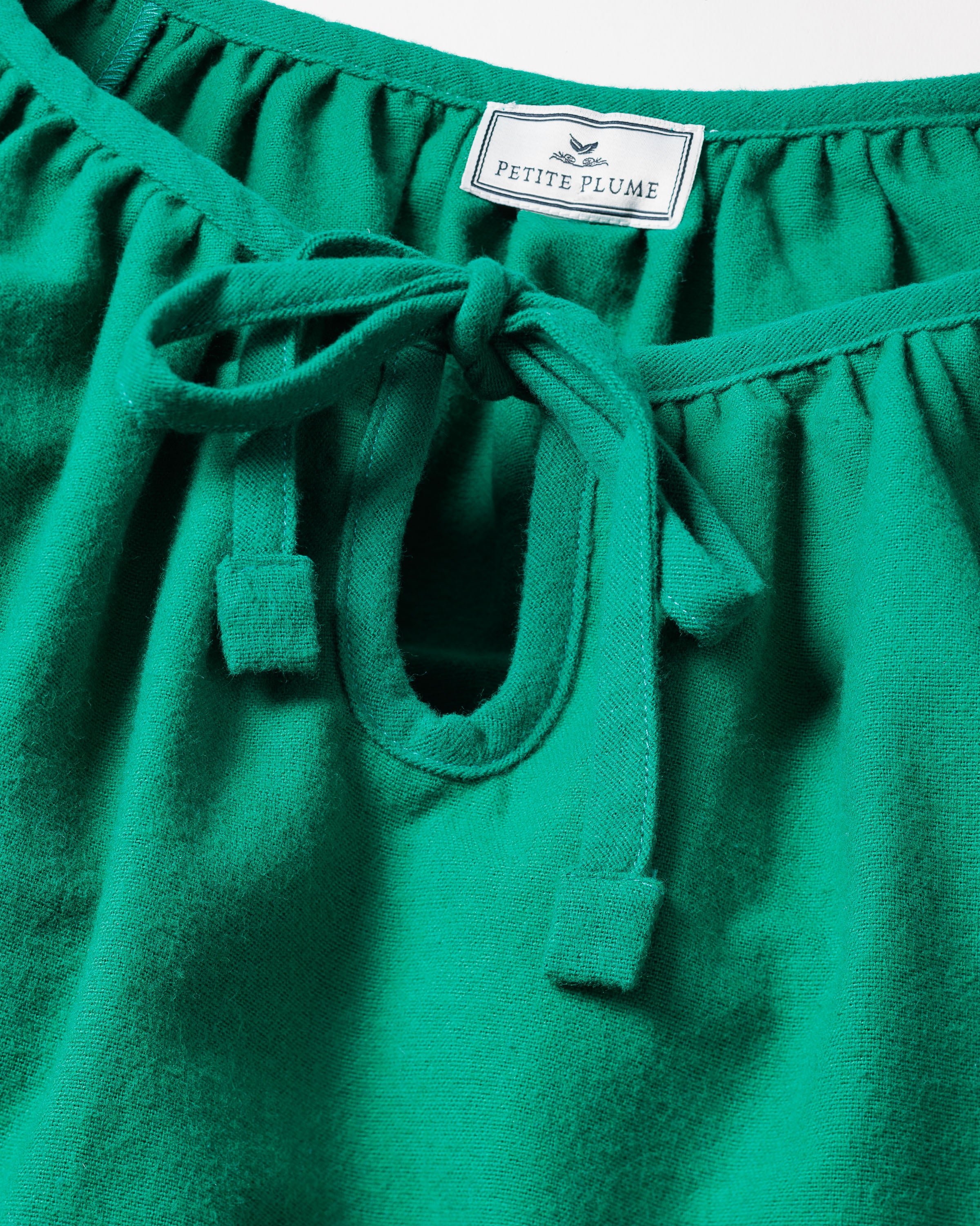 Close-up of Womens Green Flannel Delphine Nightgown featuring a drawstring neckline. The label reads Petite Plume. This cozy nightgown combines comfort and style, making it ideal sleepwear.