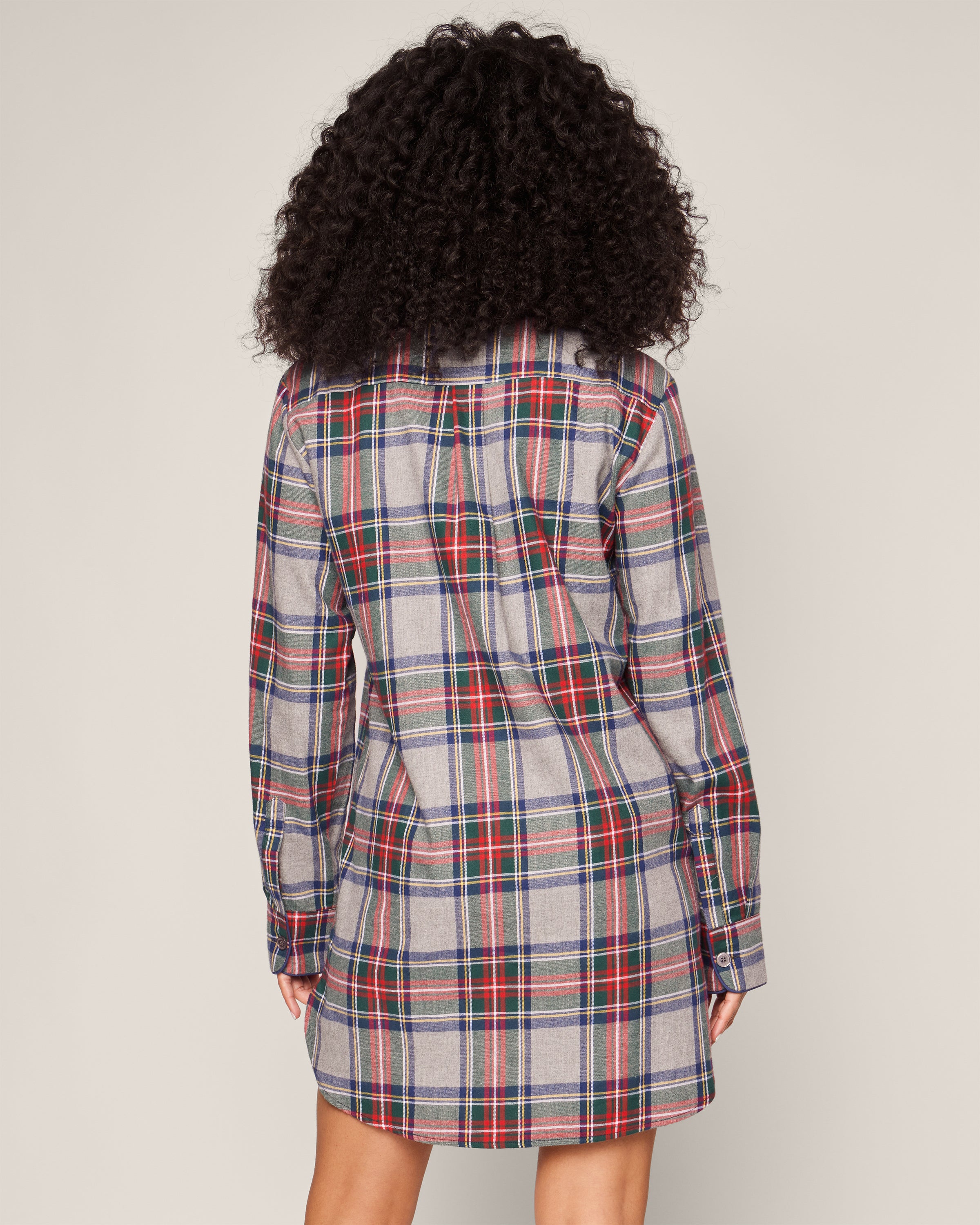 A person with curly hair is wearing Petite Plumes Womens Brushed Cotton Nightshirt in Westminster Tartan, featuring red, blue, and white stripes. They stand with their back to the camera against a plain background, subtly nodding to Scottish tradition.