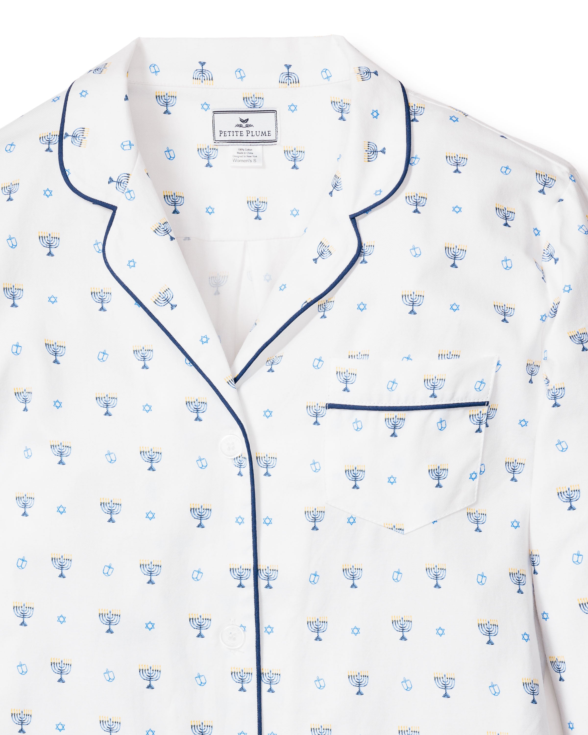 This Petite Plume Womens Twill Pajama Set in Happy Hanukkah features a white top adorned with blue and white menorah and Star of David patterns, notched collar, dark blue piping, buttons, and a small chest pocket. Made from soft cotton twill, its ideal for Hanukkah.