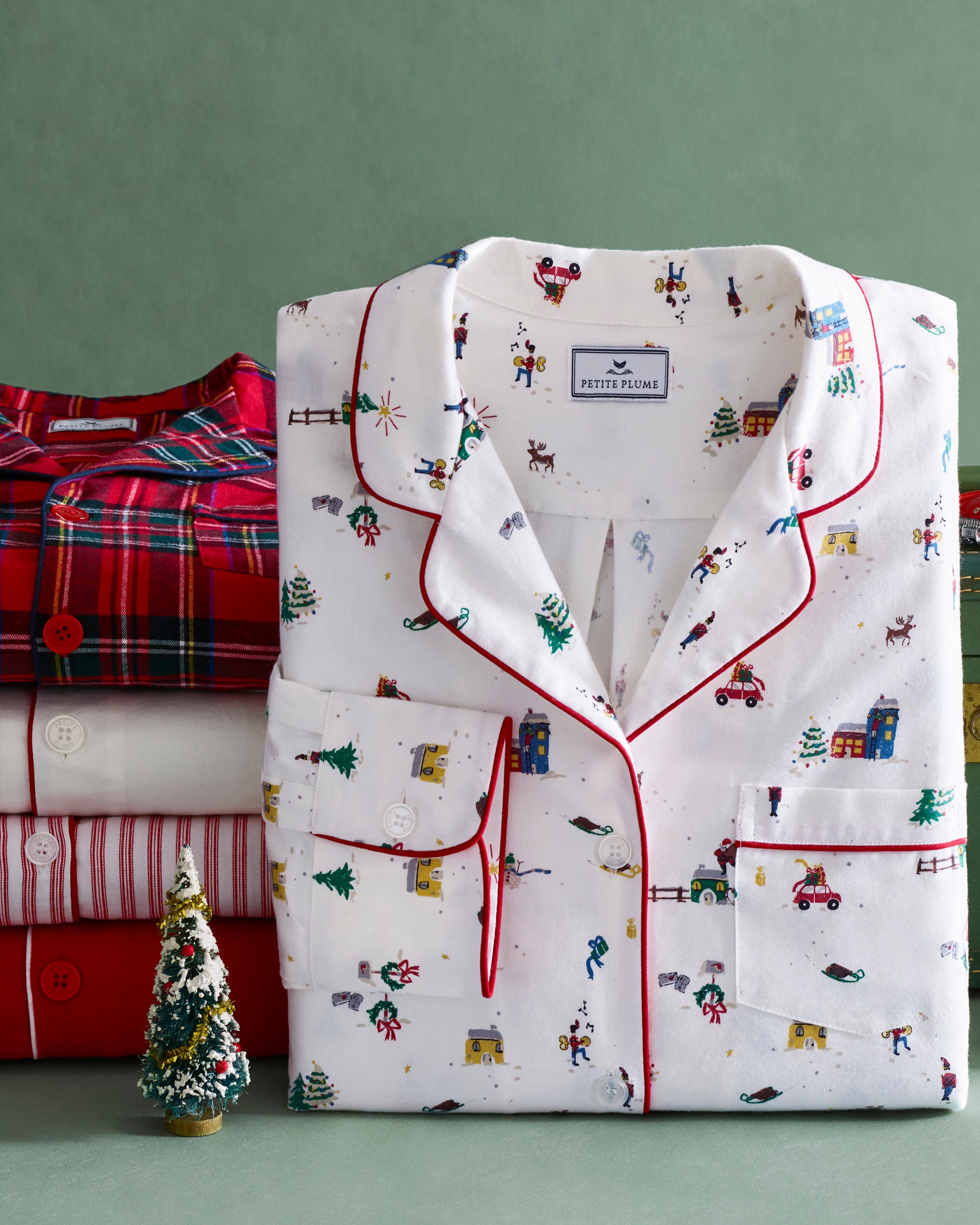 Women's Twill Pajama Set in Holiday Town: white pajama set with red piping, featuring festive prints of Christmas trees, cars, and skiers. Includes a long-sleeve button-up top with a pocket and matching drawstring pants.