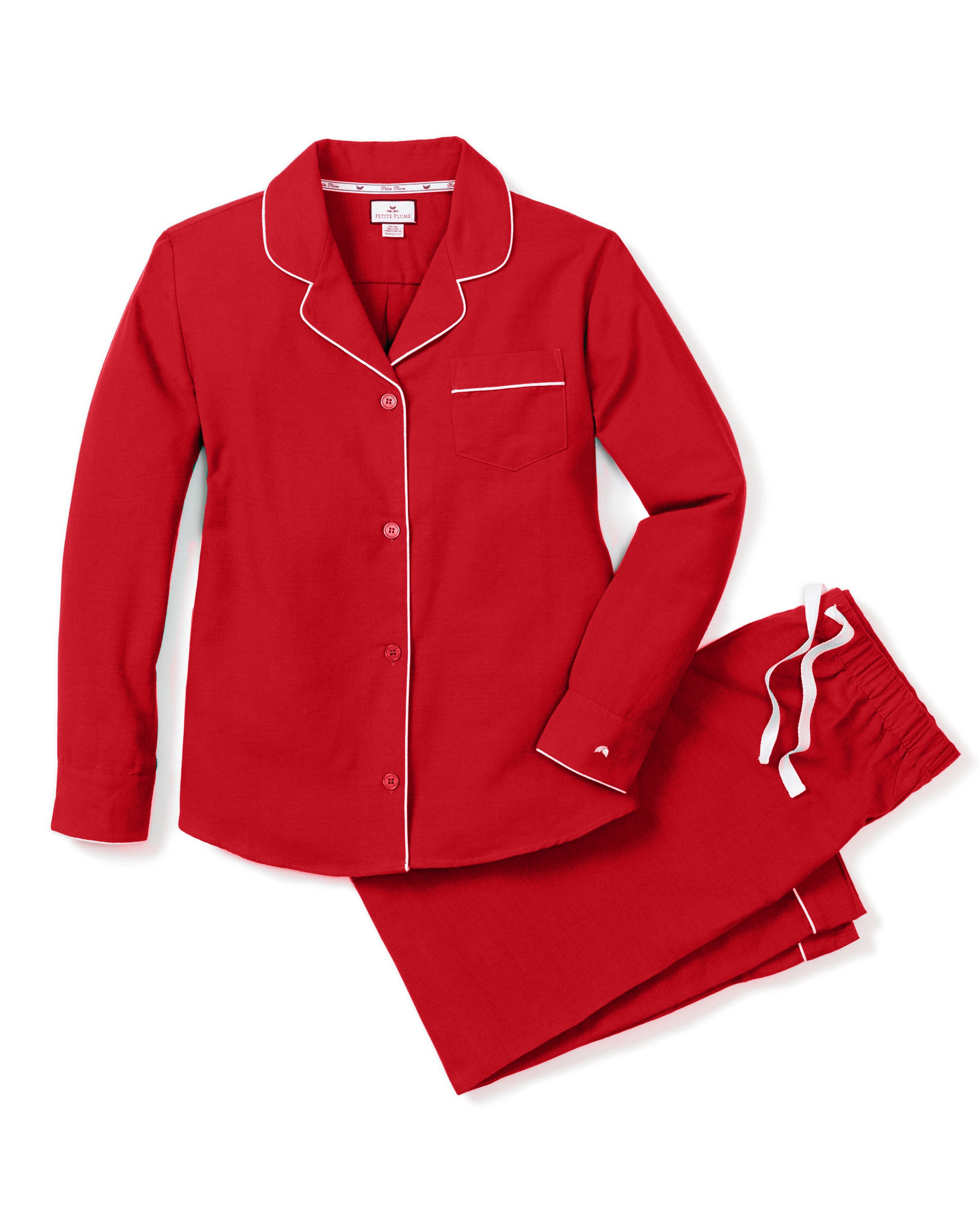 The Women’s Flannel Pajama Set in Red by Petite Plume is crafted from soft cotton and features elegant white piping. It includes a long-sleeved button-up top with a chest pocket and matching pants with an elastic waistband and white drawstring for comfort.