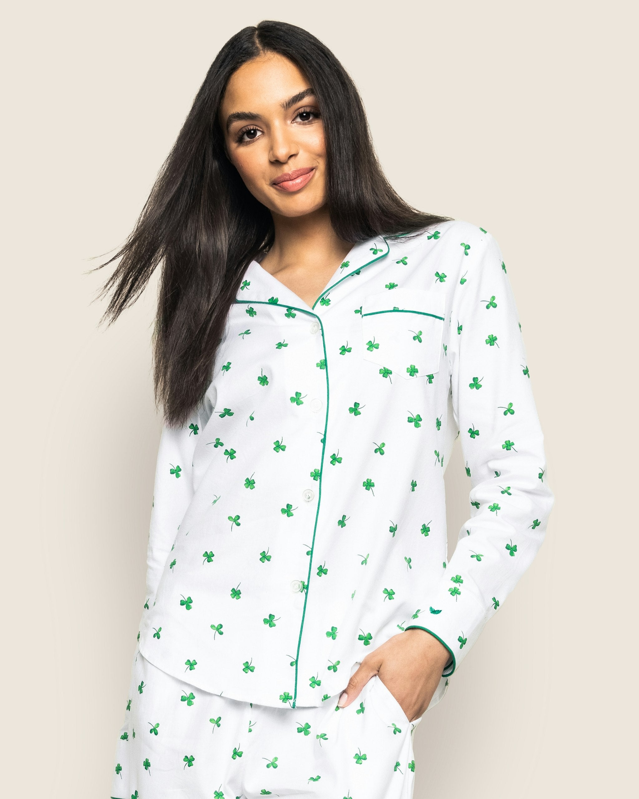 A women's pajama set with a white twill fabric featuring a green shamrock print, including a long-sleeved shirt and pants with a drawstring.