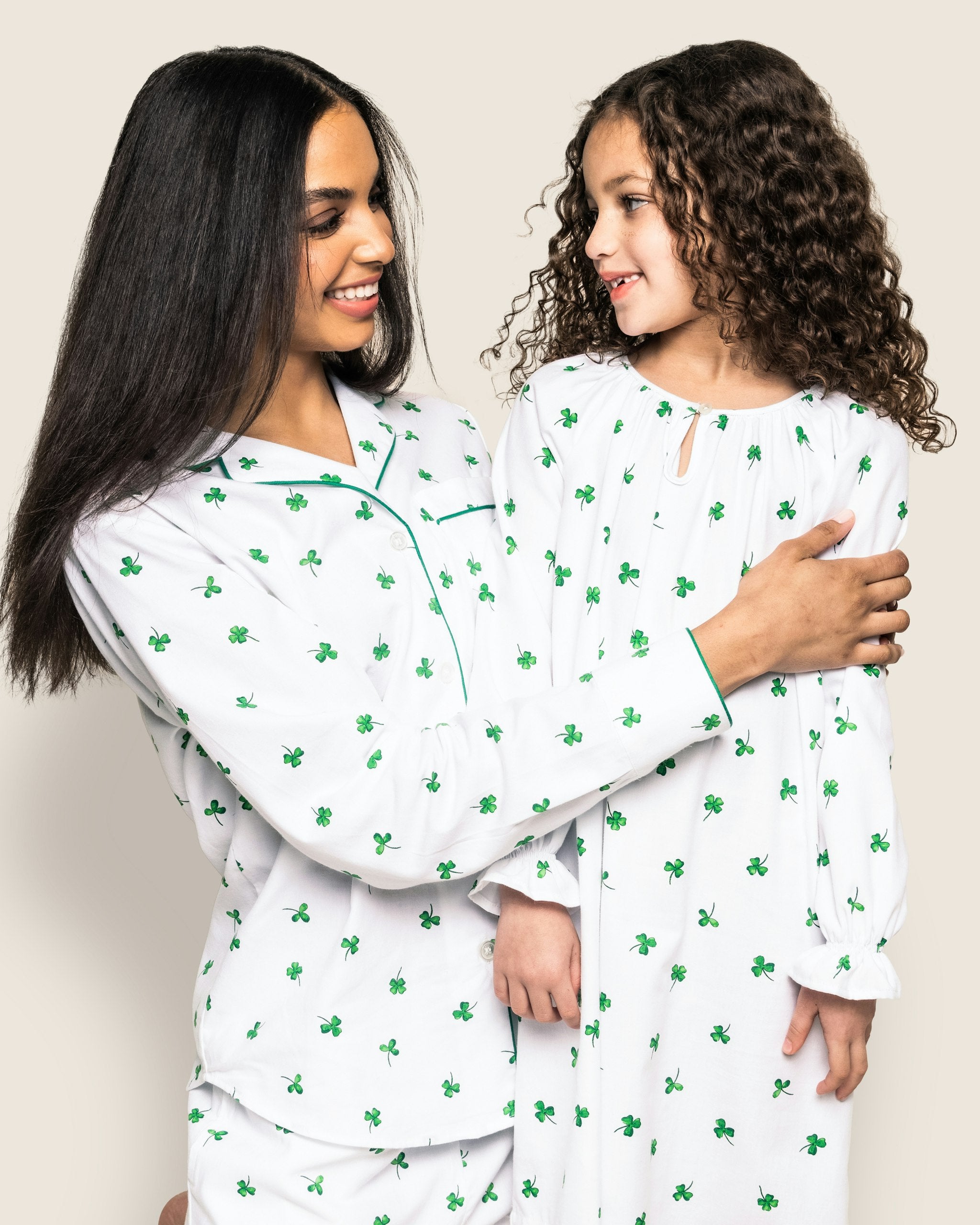 A women's pajama set with a white twill fabric featuring a green shamrock print, including a long-sleeved shirt and pants with a drawstring.