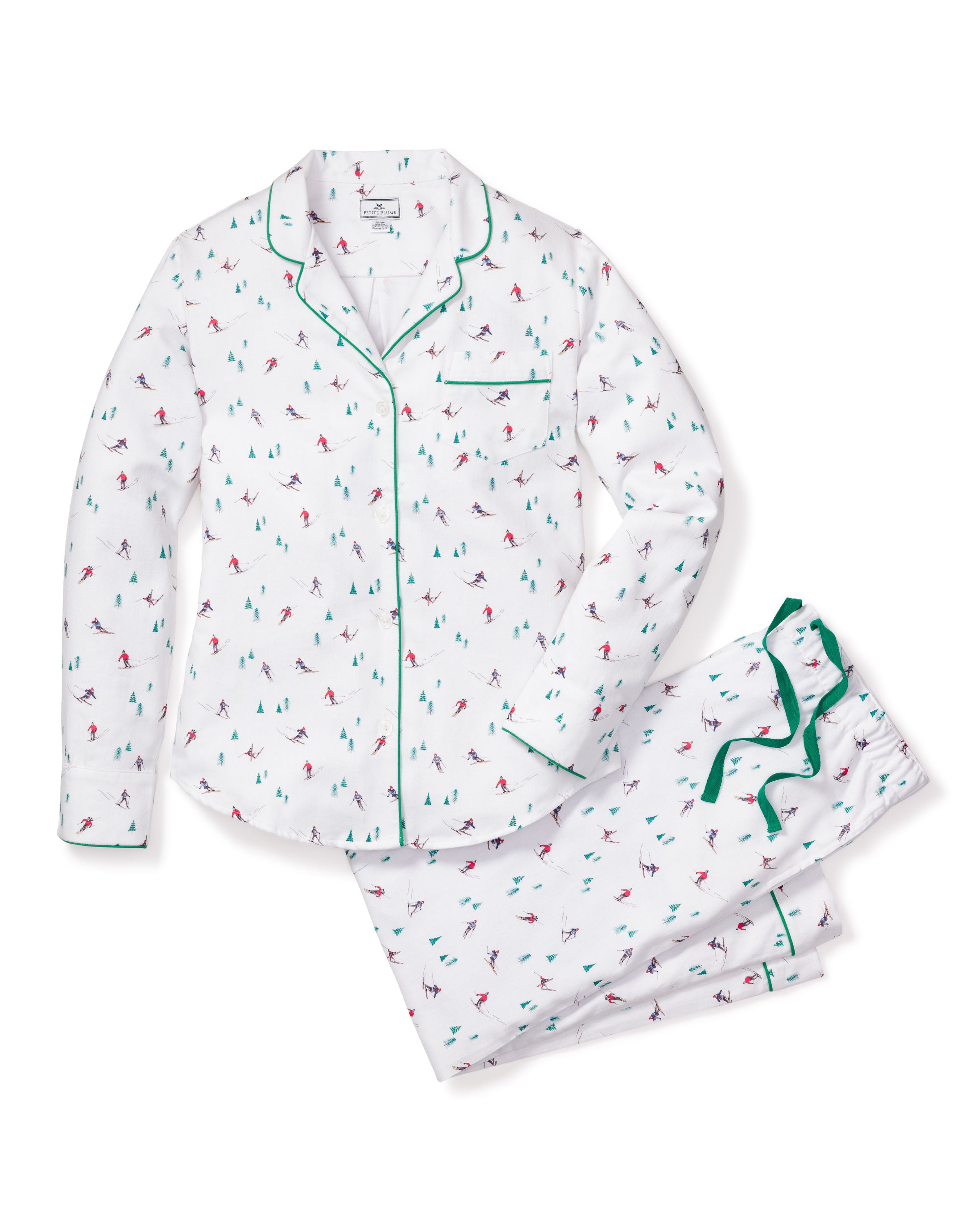 Petite Plumes Womens Flannel Pajama Set in Après Ski features white pajamas adorned with holiday-themed red and green skiers. Made from brushed cotton flannel, it includes a long-sleeve button-up top with a chest pocket and matching pants with an elastic waistband, highlighted by green piping edges.
