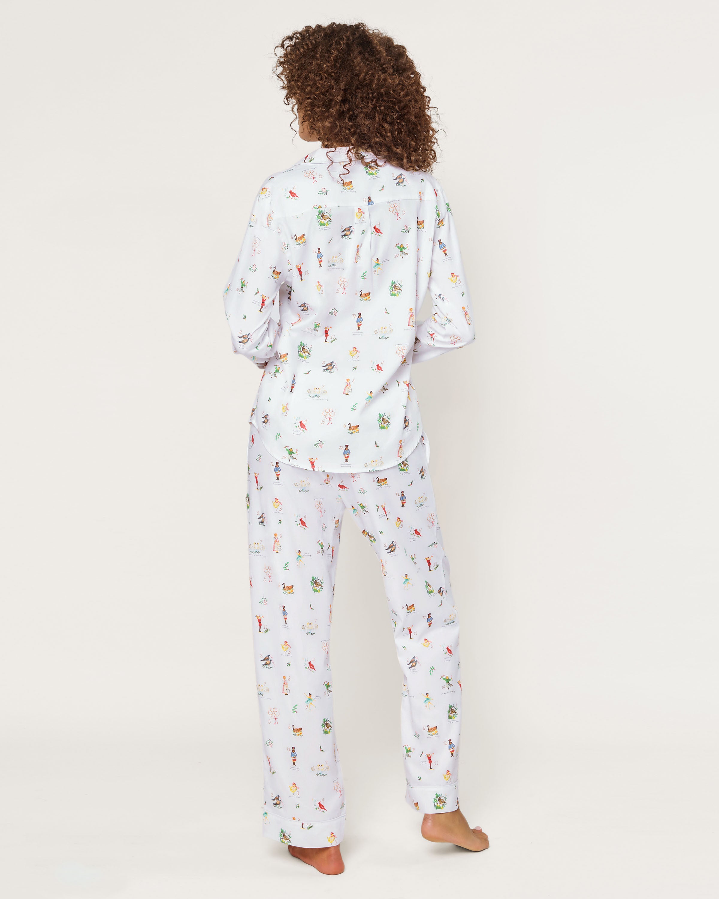 Women's Twill Pajama Set in 12 Days of Christmas features a white button-up long sleeve top and pants, adorned with a playful pattern of multicolored animals and palm trees.