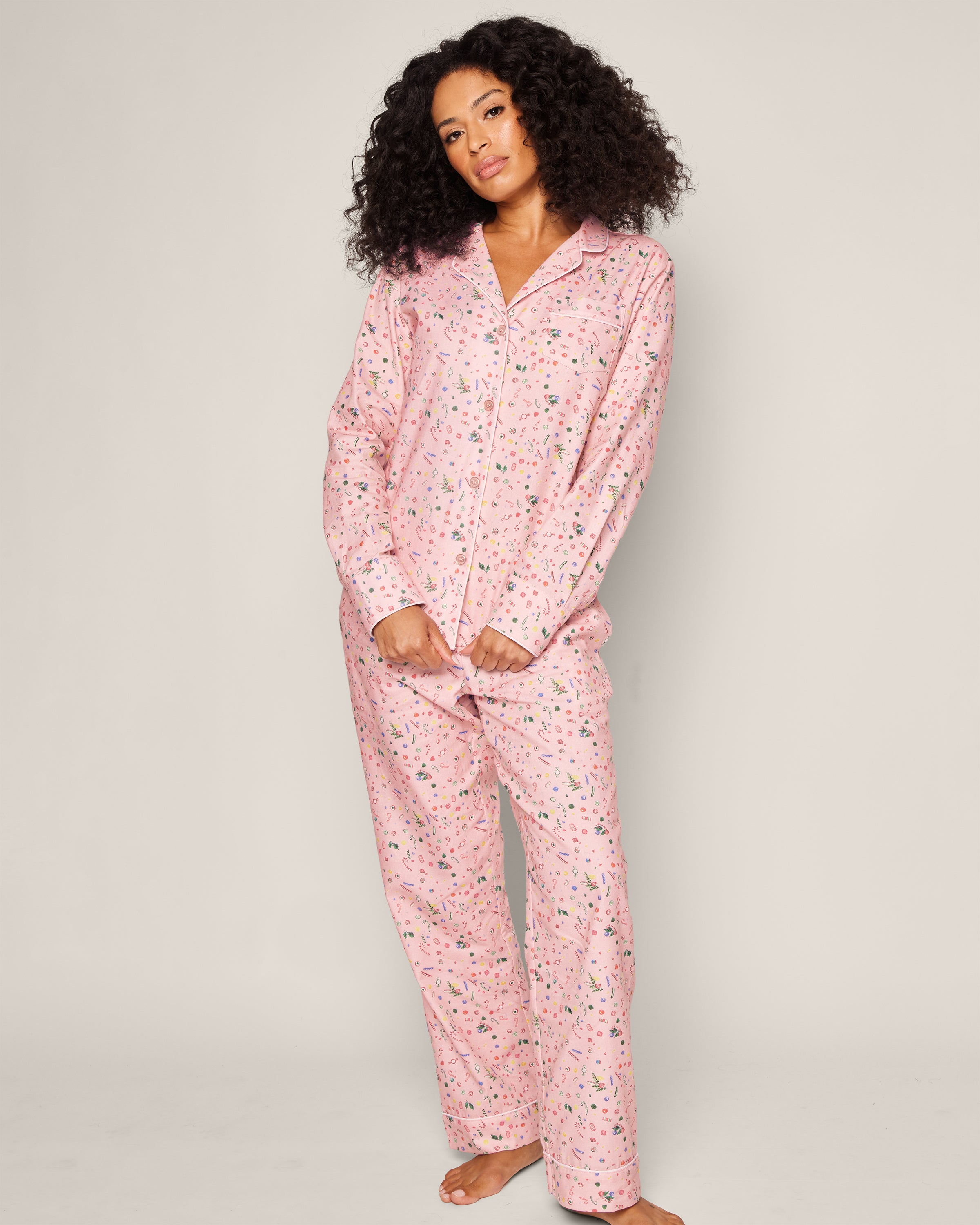 A person wearing the Womens Twill Pajama Set in Vintage Sweets by Petite Plume stands barefoot against a plain background, looking relaxed and casual.