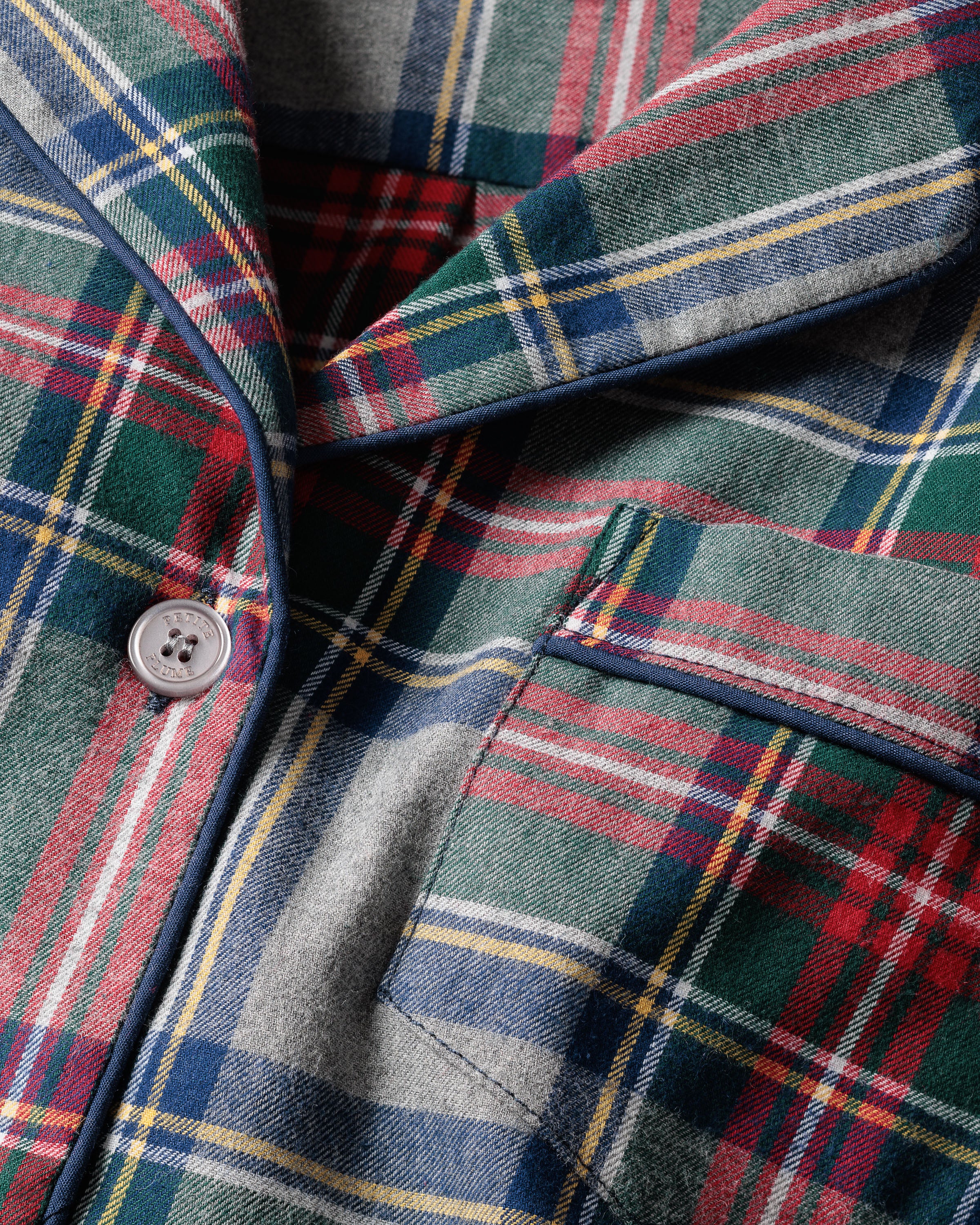 The image highlights the Womens Brushed Cotton Pajama Set in Westminster Tartan by Petite Plume, featuring a green, red, yellow, and blue plaid design with a checkered motif. The garment is 100% cotton with a white button and pocket piping, offering a soft, wool-like brushed twill texture.