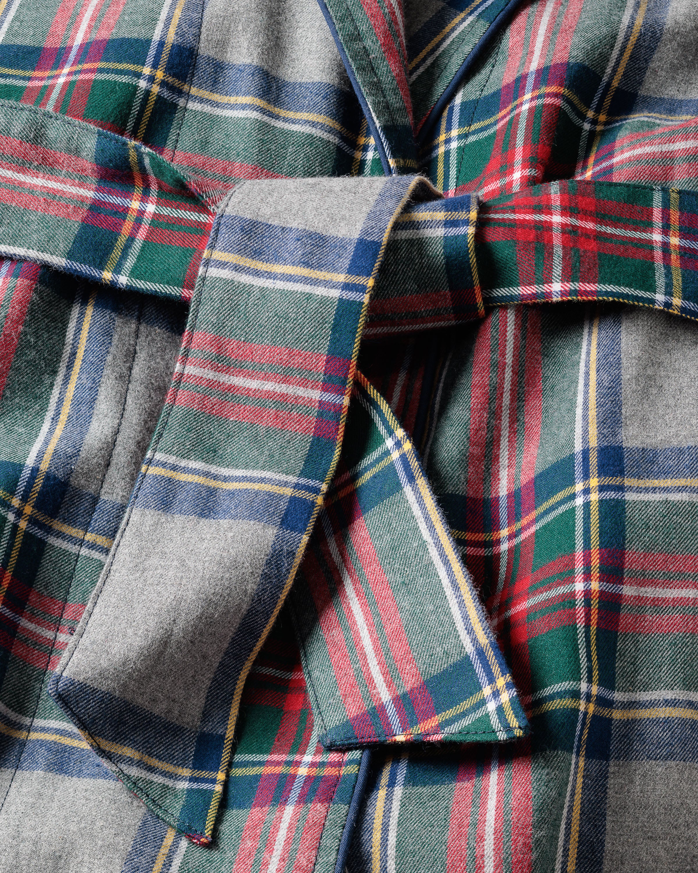 Close-up of Petite Plumes Womens Brushed Cotton Robe in Westminster Tartan, featuring plaid flannel fabric with overlapping green, red, blue, and yellow patterns. A loosely knotted belt evokes classic Scottish tradition.