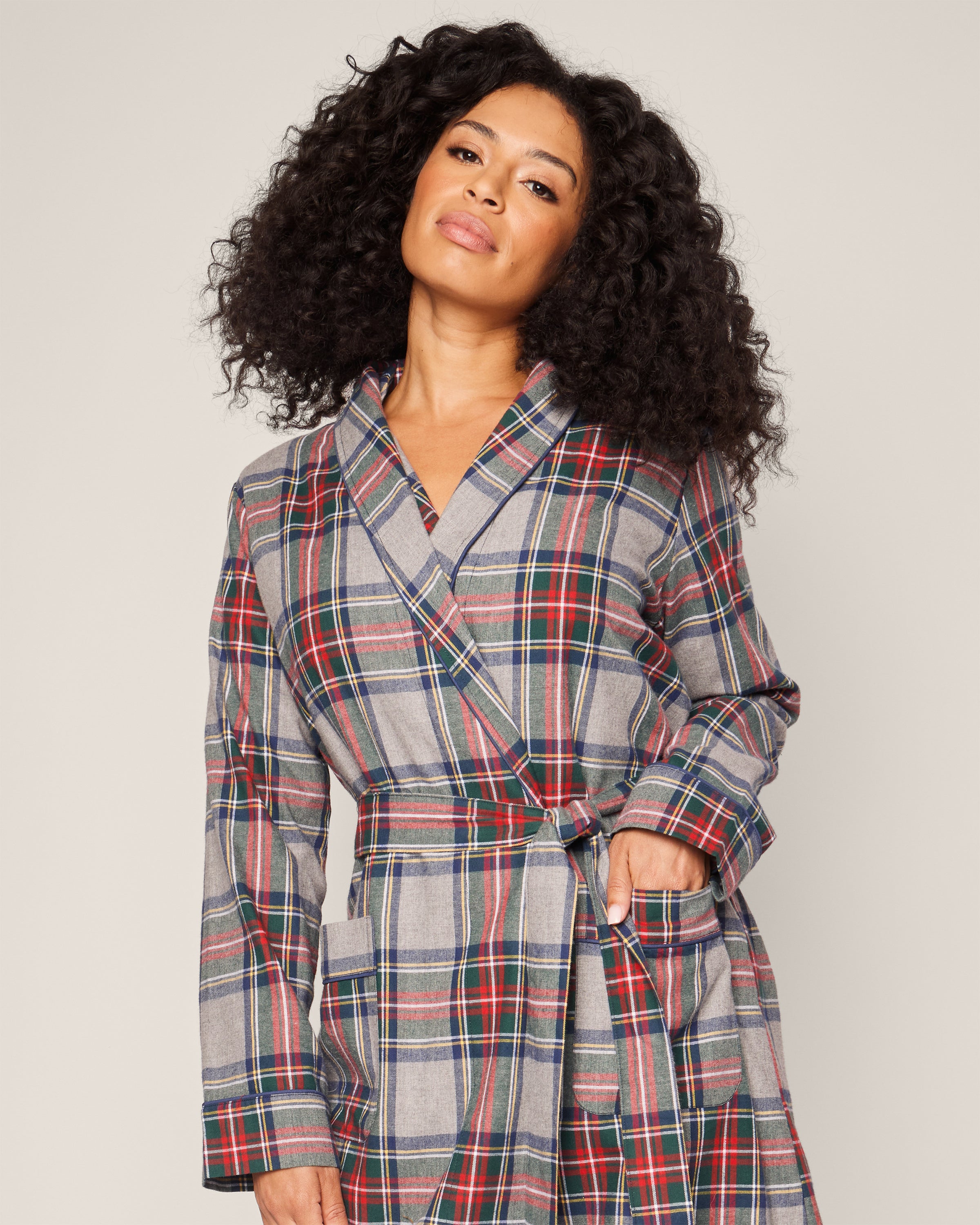 A person with long, curly hair confidently models the Womens Brushed Cotton Robe in Westminster Tartan by Petite Plume, showcasing the richness of red, blue, and green. Against a plain background, the robe embodies elegant luxury sleepwear with a Scottish heritage.