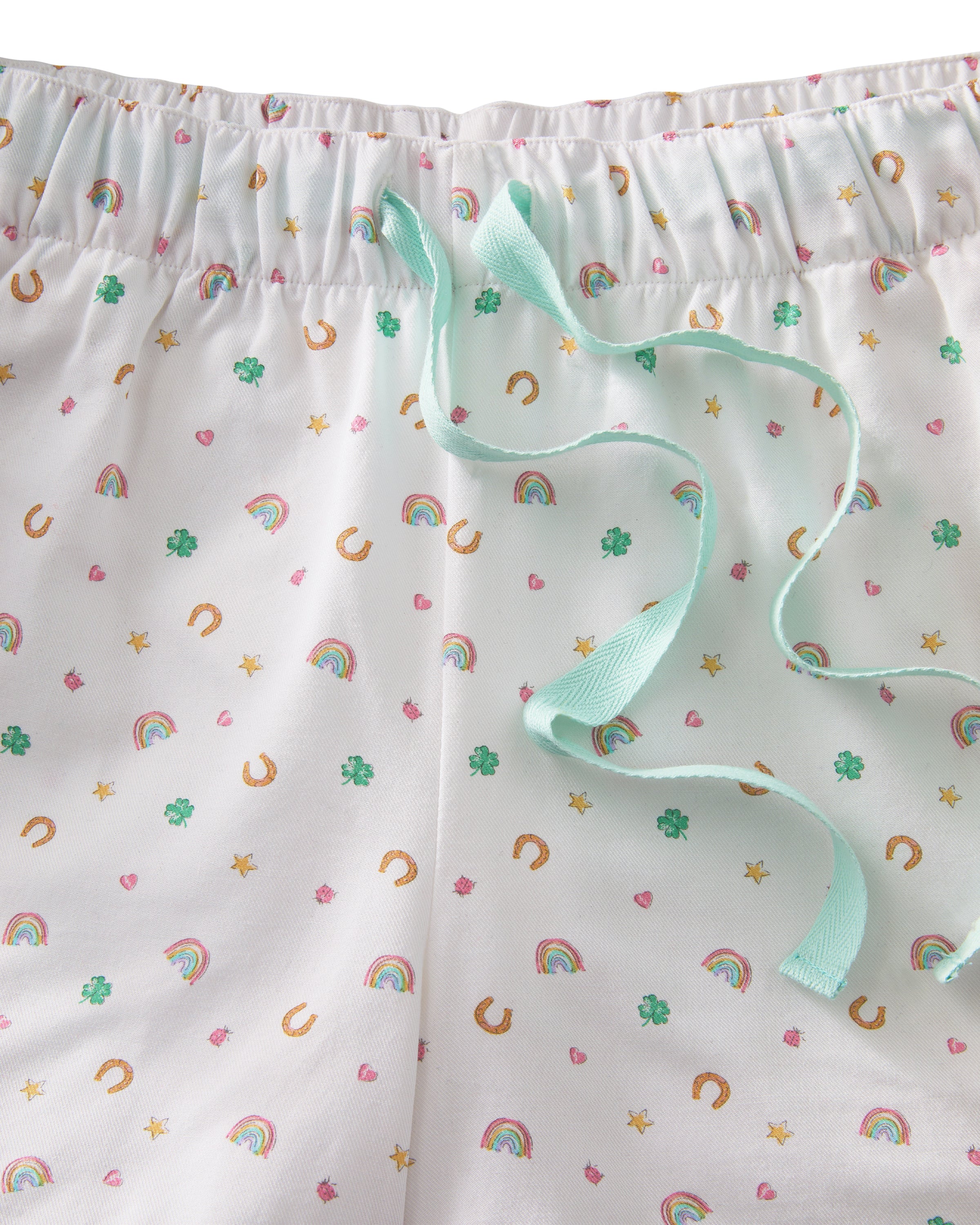 A woman with long, wavy blonde hair wears the Women's Twill Short Sleeve Short Set in Good Luck Charms, featuring a multicolored pattern, standing against a plain light background.