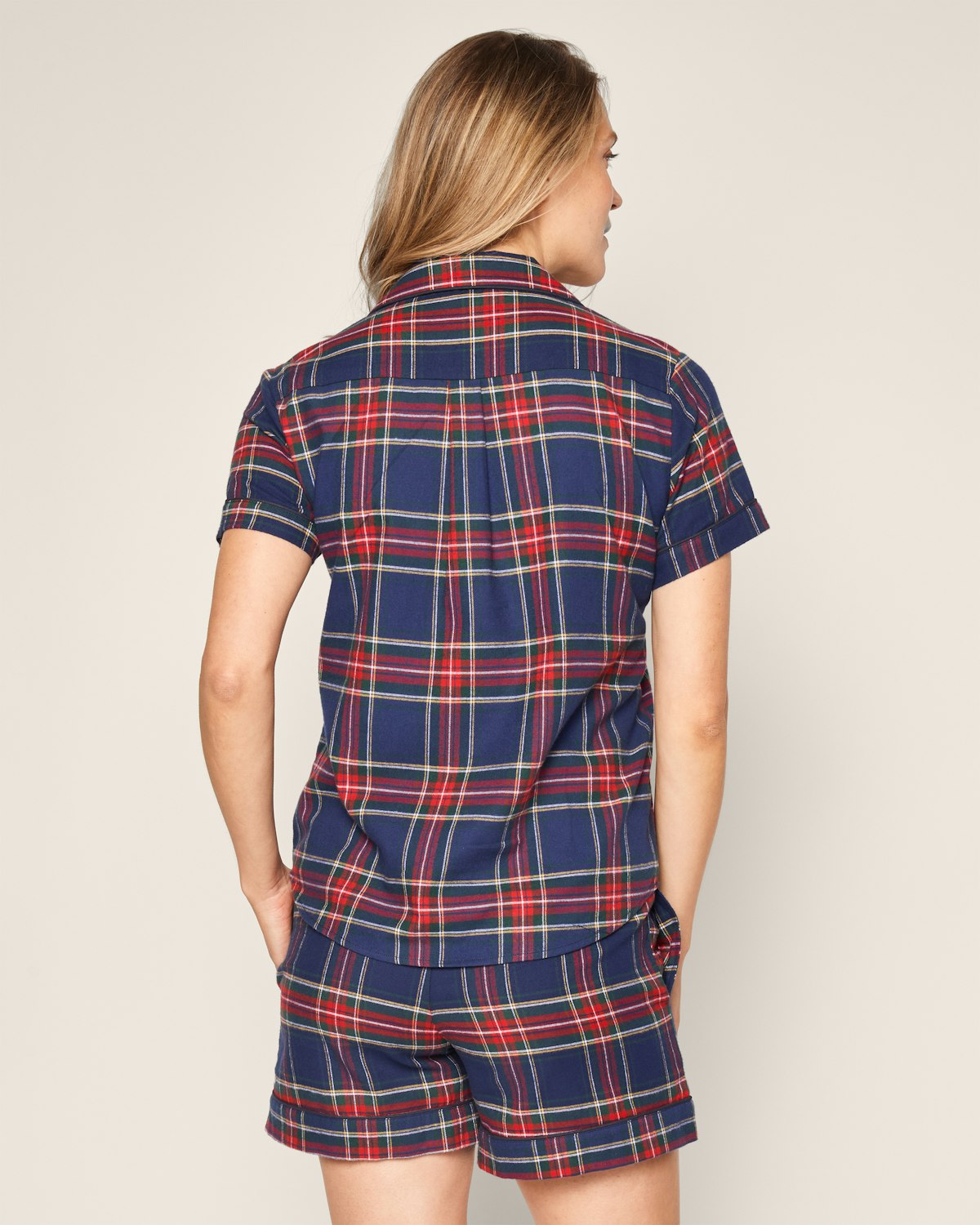 With long hair, a person is seen from behind wearing the Petite Plume Womens Brushed Cotton Windsor Tartan Pajama Short and Pants Set in blue, red, and yellow plaid against a light background.