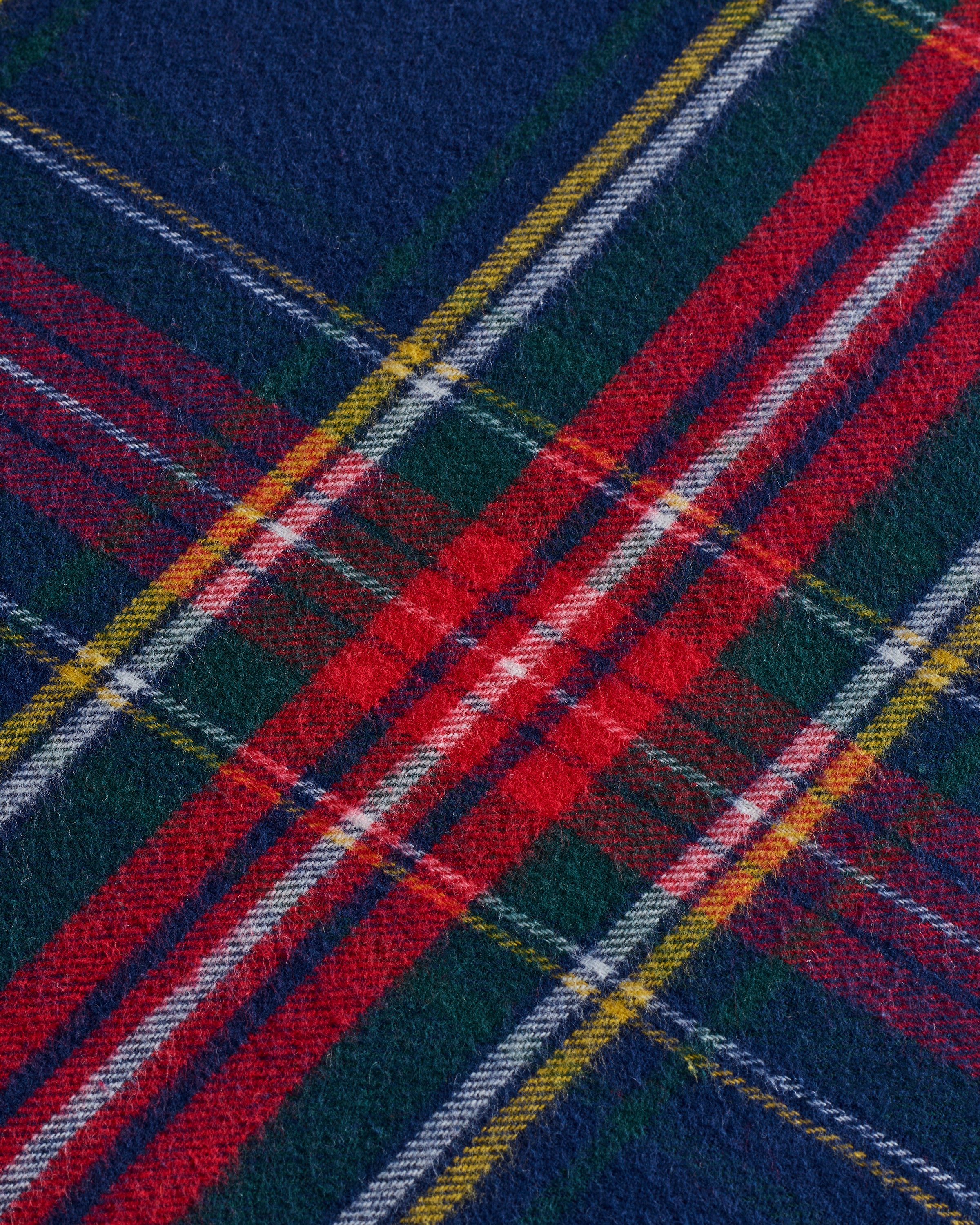 Close-up of Petite Plumes Flannel Crib Sheet in Windsor Tartan, featuring a vibrant plaid pattern with intersecting stripes in red, blue, green, yellow, and white reminiscent of cozy flannel.