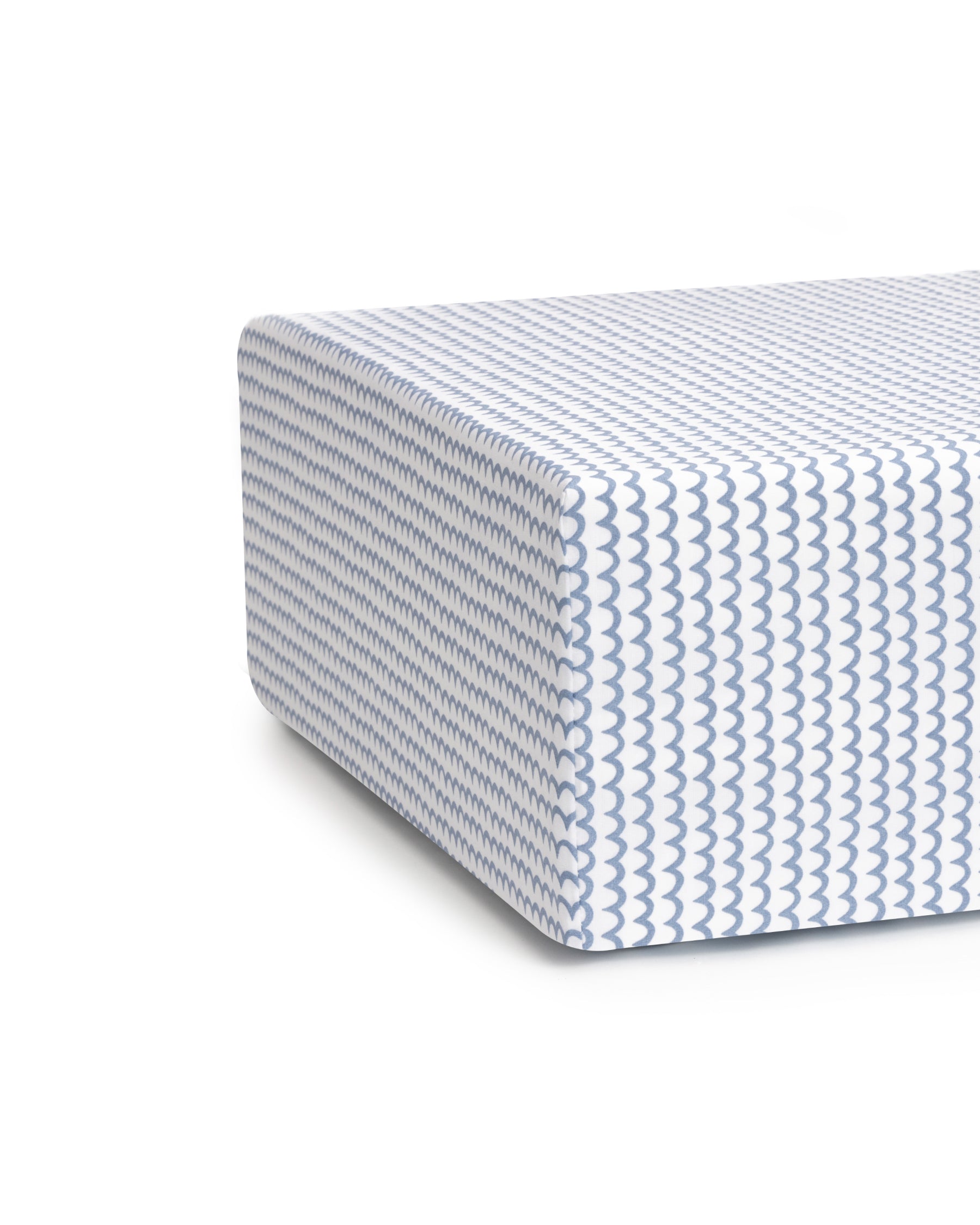 Close-up of Luxe Premium La Mer Crib Sheet by Petite Plume, showcasing an ultra-soft white fabric with a blue wave pattern. The sheet resembles a thick, modern mattress corner and sits on a breathable white backdrop.