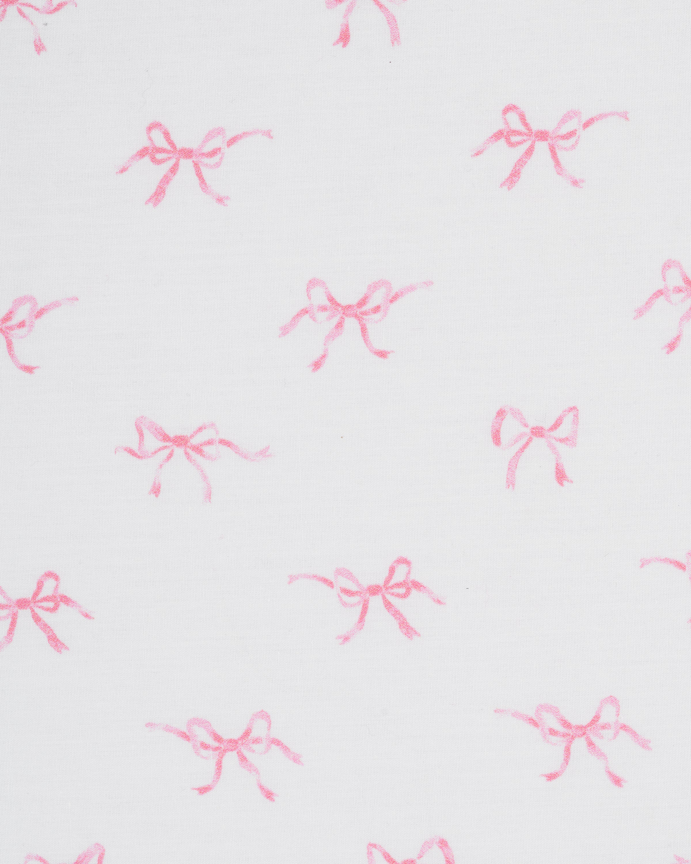 A close-up of the Luxe Premium Percale Crib Sheet in Blushing Bows, featuring a white background with a pattern of small pink ballerinas, neatly wrapped around the corner of a crib mattress.