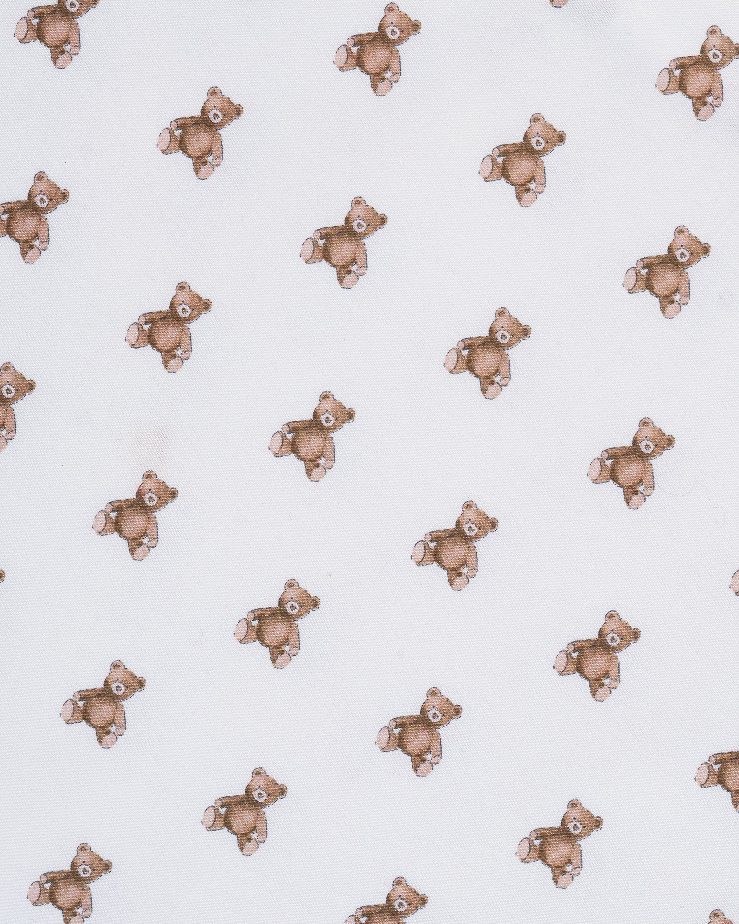 A close-up of the Luxe Premium Percale Crib Sheet in Teddy Tales, featuring a small repeating brown and orange floral pattern on white, smoothly wrapped around a mattress corner.