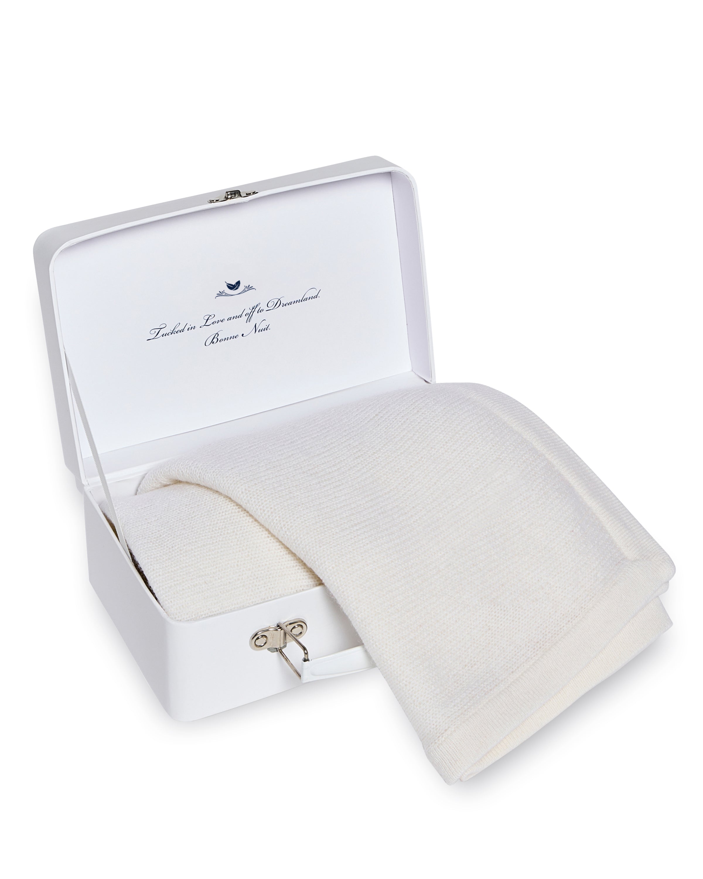 The Petite Plume Cashmere Baby Blanket in Ivory is nestled inside an open white box with a front latch and printed text on the inner lid, perfect as a luxury keepsake and ideal baby gift.