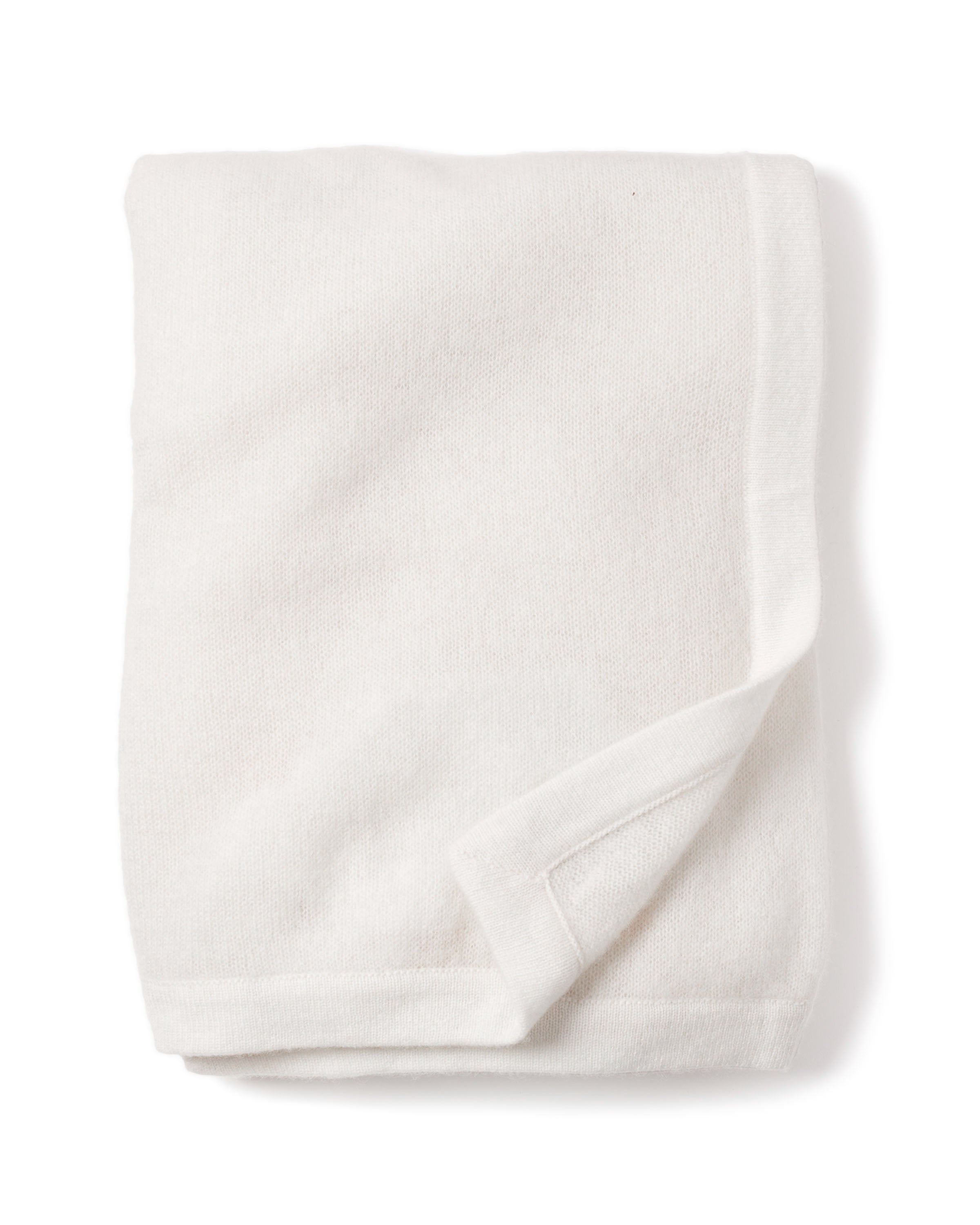 A Cashmere Baby Blanket in Ivory by Petite Plume, artfully showcased against a plain white background, with one edge slightly lifted to reveal its soft texture—ideal for those seeking the perfect luxury baby gift.
