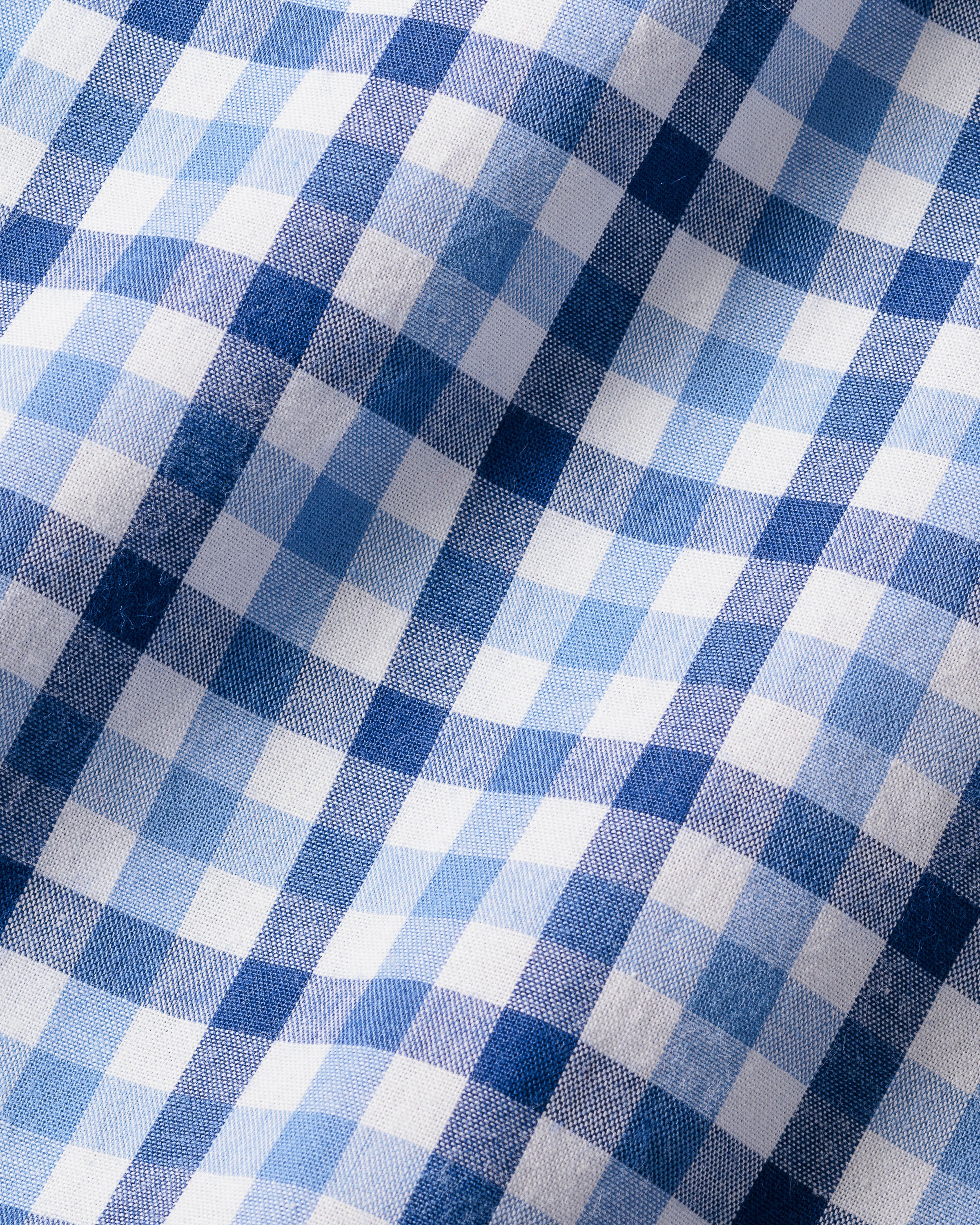 The Girls Twill Amelie Nightgown by Petite Plume showcases a royal blue gingham pattern with alternating light and dark yarn-dyed cotton squares. Soft and textured, this material offers gentle folds, ideal for cozy sleepwear.