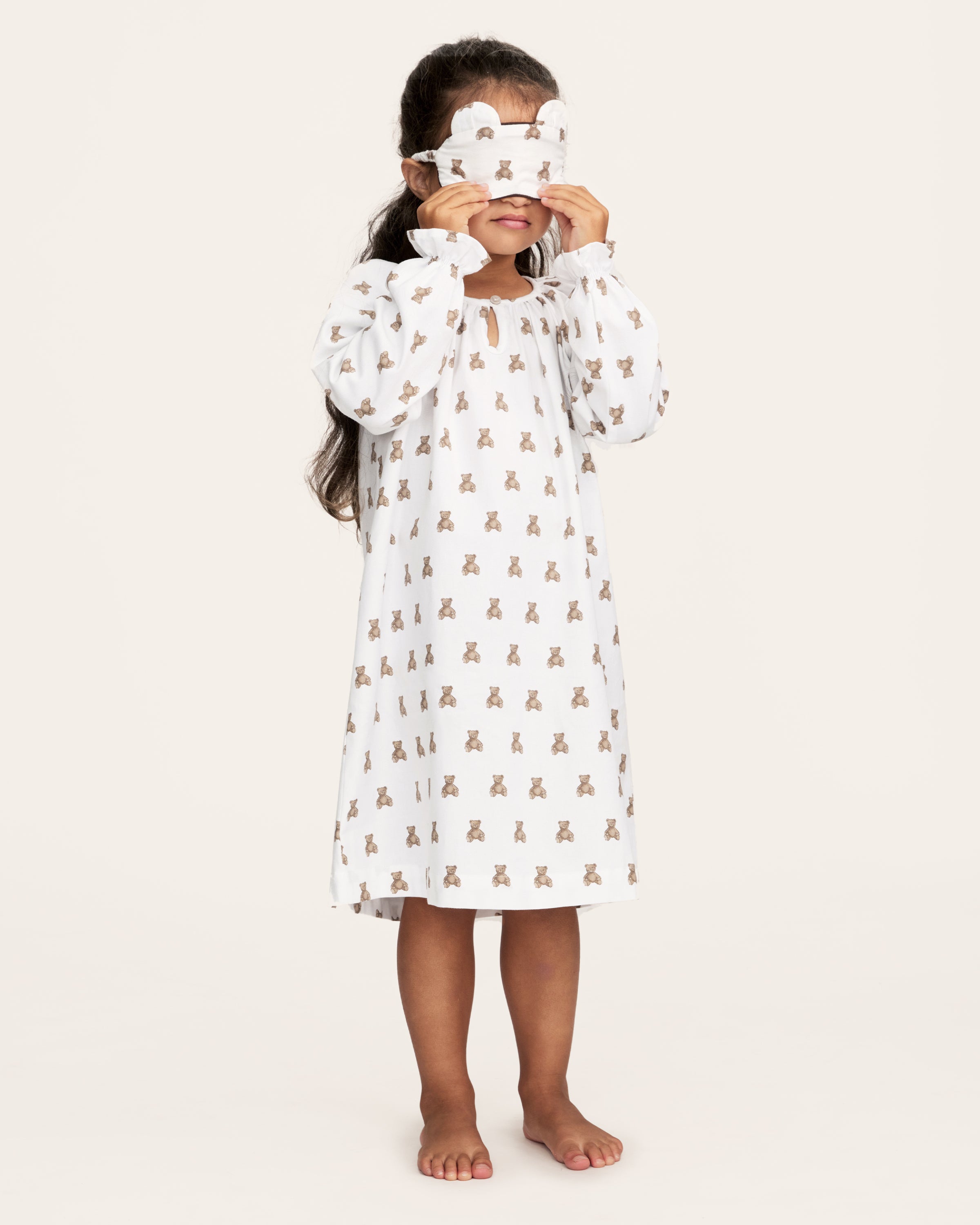 The Girl's Twill Delphine Nightgown in Teddy Tales features long sleeves, a white fabric with an all-over brown teddy bear print, a gathered neckline, ruffled cuffs, and a button closure at the collar.
