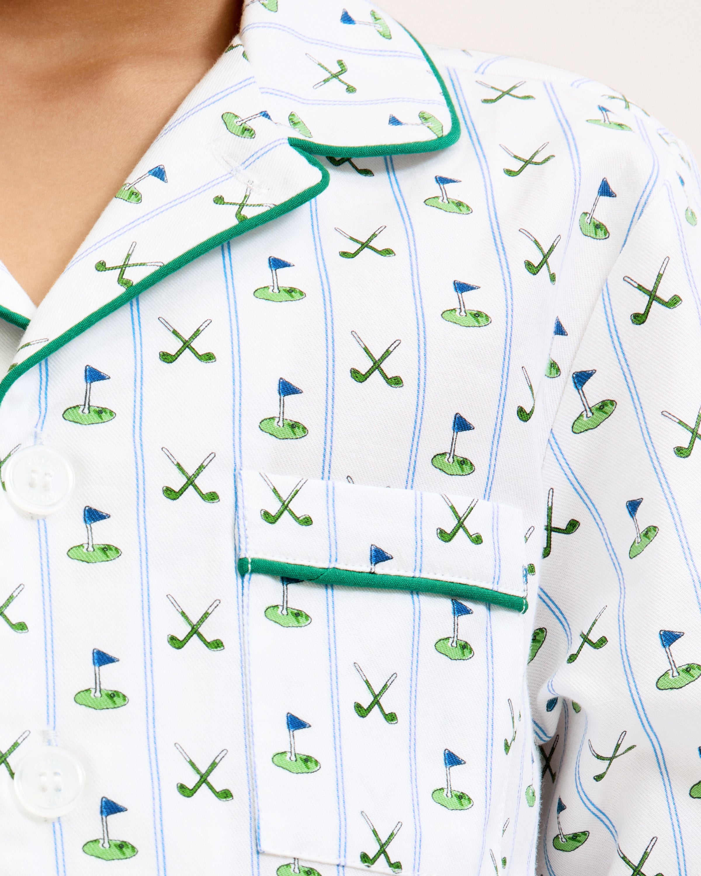The Kid's Twill Pajama Set in Fairway Stripe features white pajamas with green piping, a tennis racket and green stripe pattern, a long-sleeve button-up top with a chest pocket, and matching long pants.