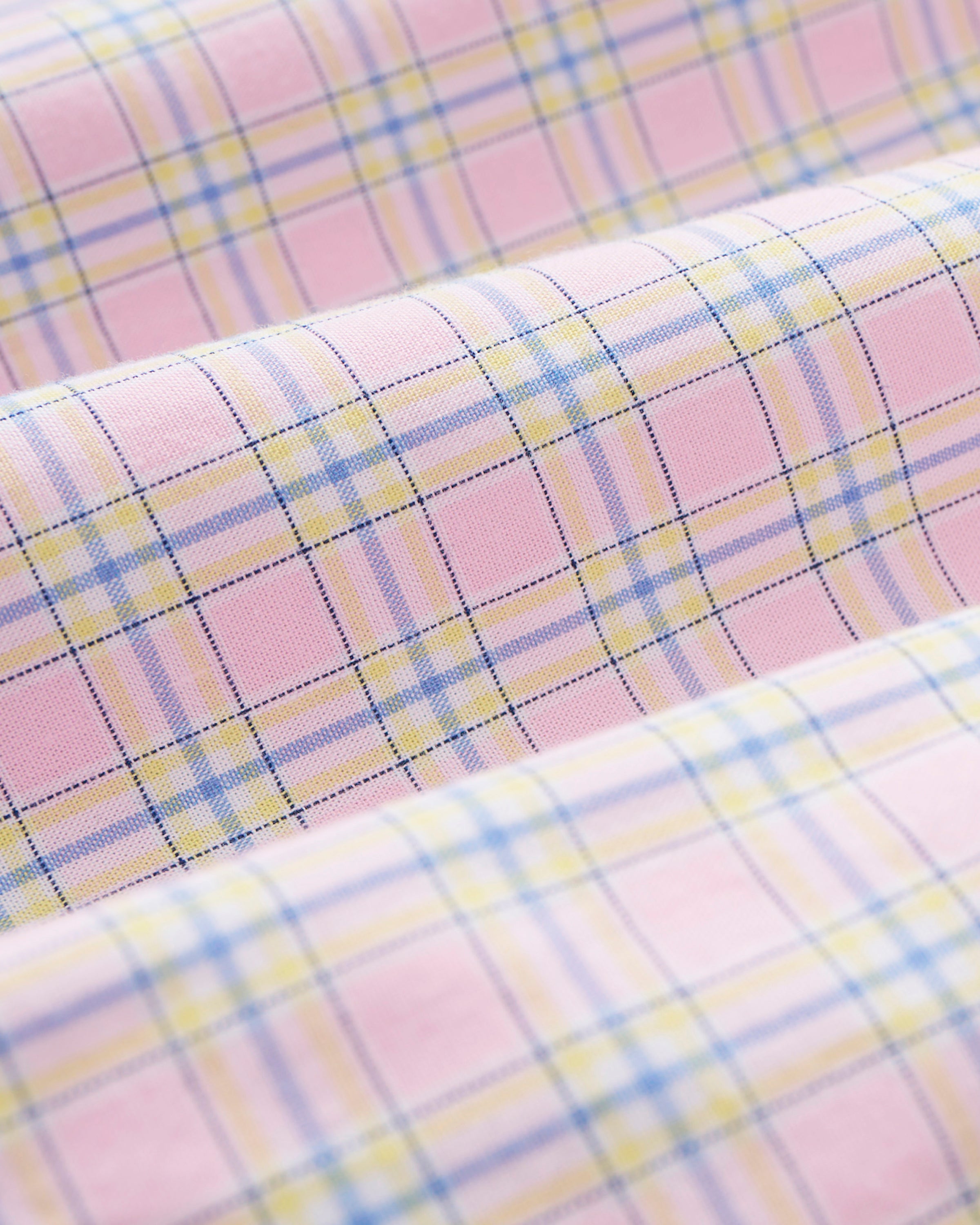 Young girl with long blonde hair wears the Kid's Twill Colette Pajama Set in Peony Plaid, featuring pink and white checks, scalloped edges, and stands barefoot against a plain light background.