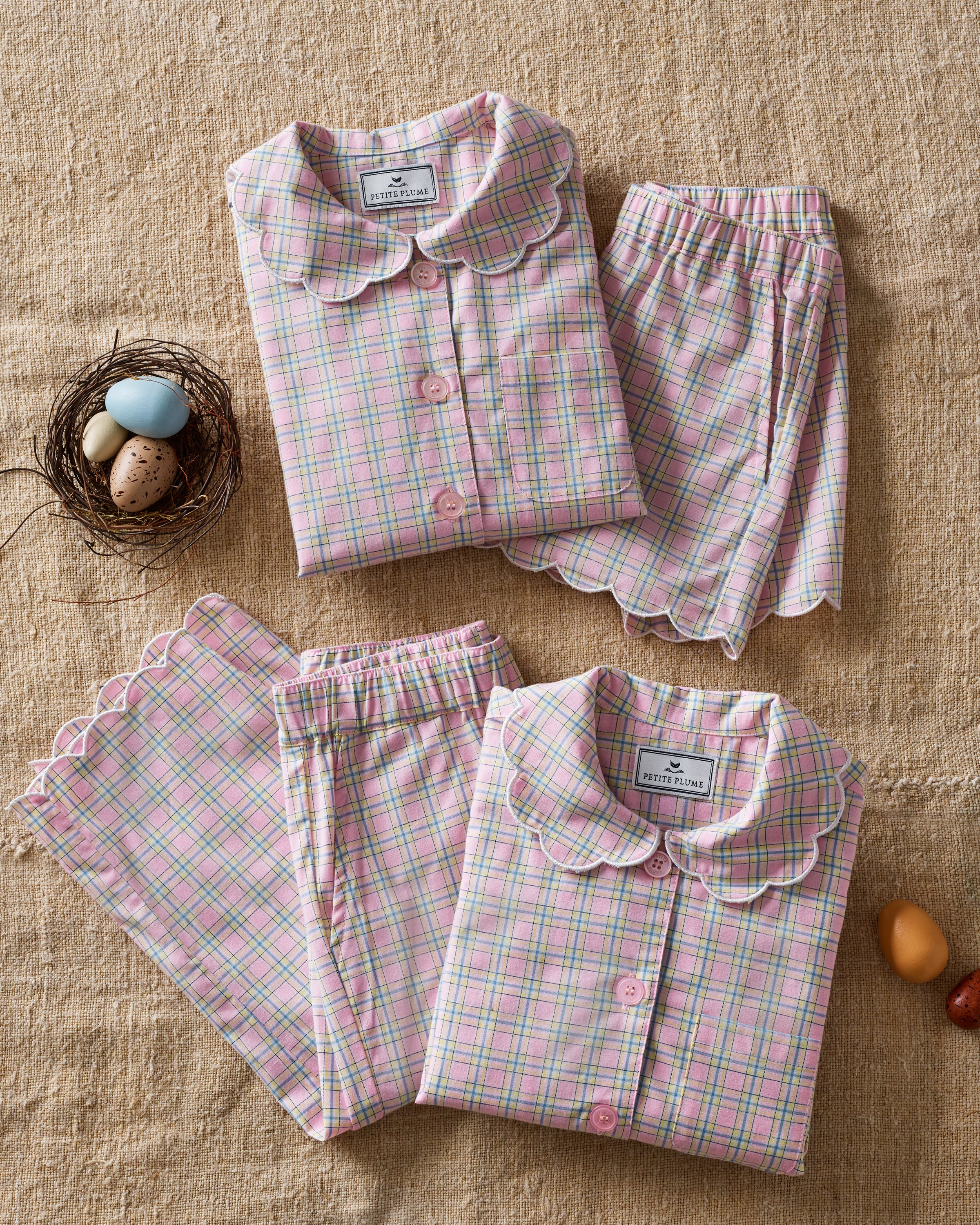 Young girl with long blonde hair wears the Kid's Twill Colette Pajama Set in Peony Plaid, featuring pink and white checks, scalloped edges, and stands barefoot against a plain light background.