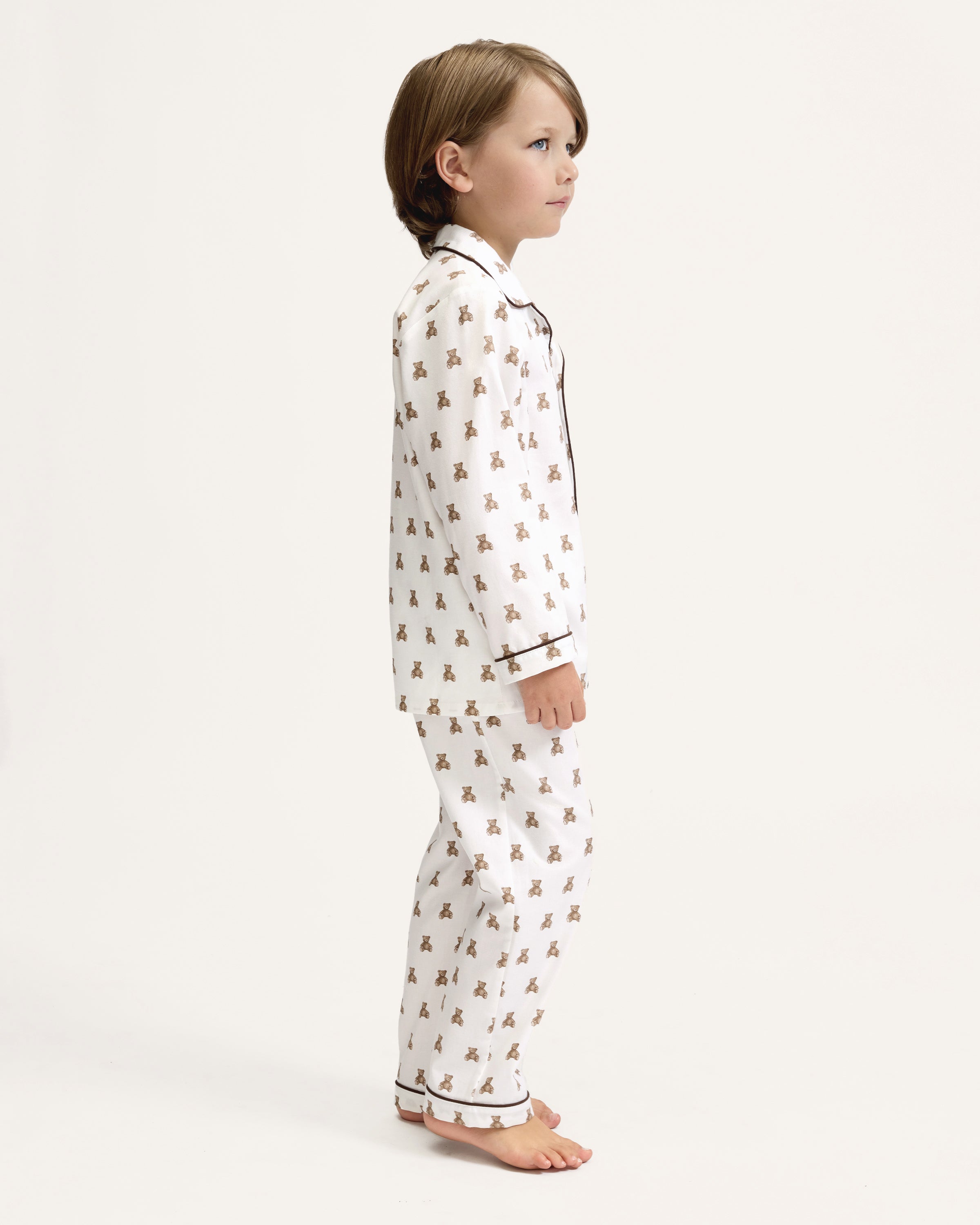 Kid's Twill Pajama Set in Teddy Tales: white long-sleeve, button-up pajamas with pants, featuring brown teddy bear print, dark piping along edges and chest pocket.