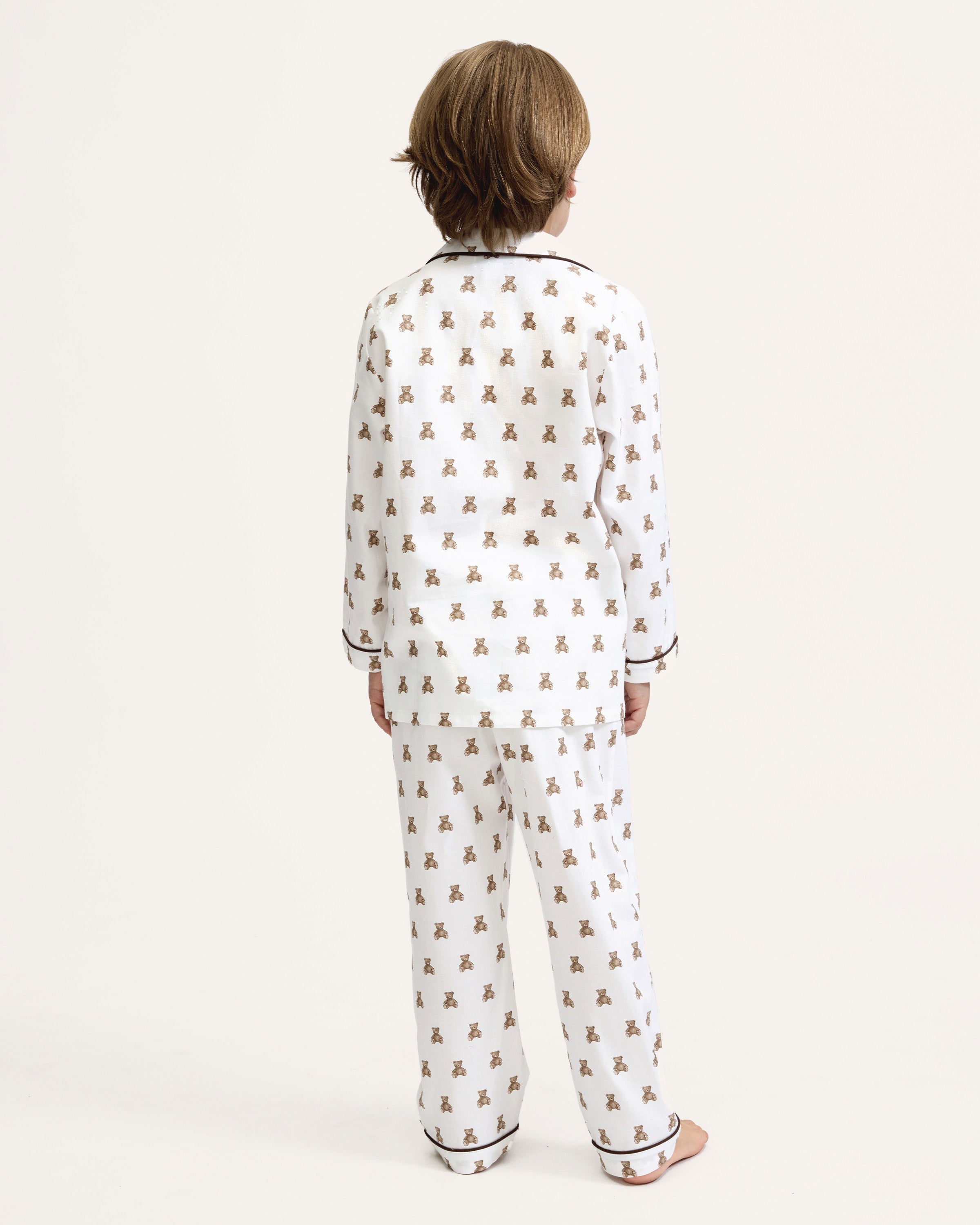 Kid's Twill Pajama Set in Teddy Tales: white long-sleeve, button-up pajamas with pants, featuring brown teddy bear print, dark piping along edges and chest pocket.
