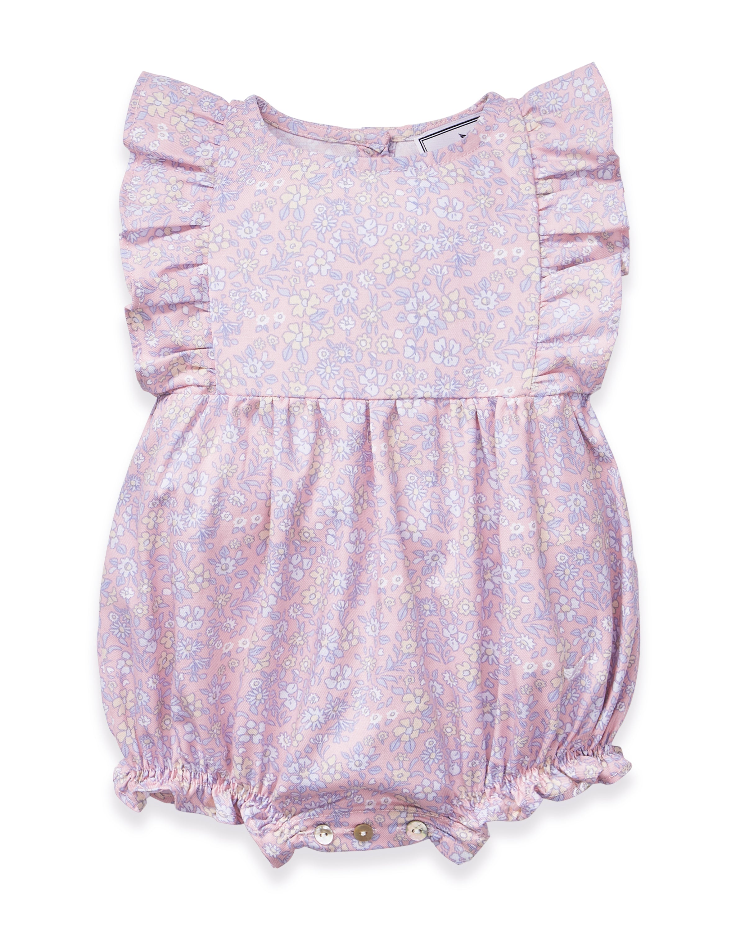 A curly-haired toddler stands barefoot, pointing left and looking that way, wearing the Baby's Twill Ruffled Romper in Fleur Blush against a plain light background.