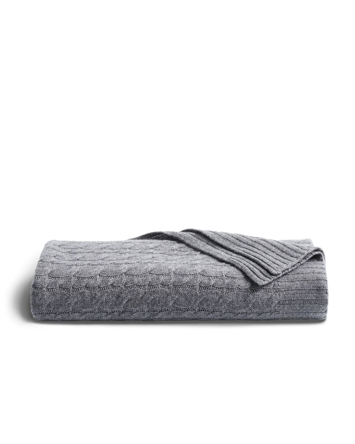 The Petite Plume Cashmere Cable Knit Throw in Dark Grey, elegantly textured with a ribbed edge, is displayed against white. This cozy, giftable piece enhances any home decor with its sophisticated design.