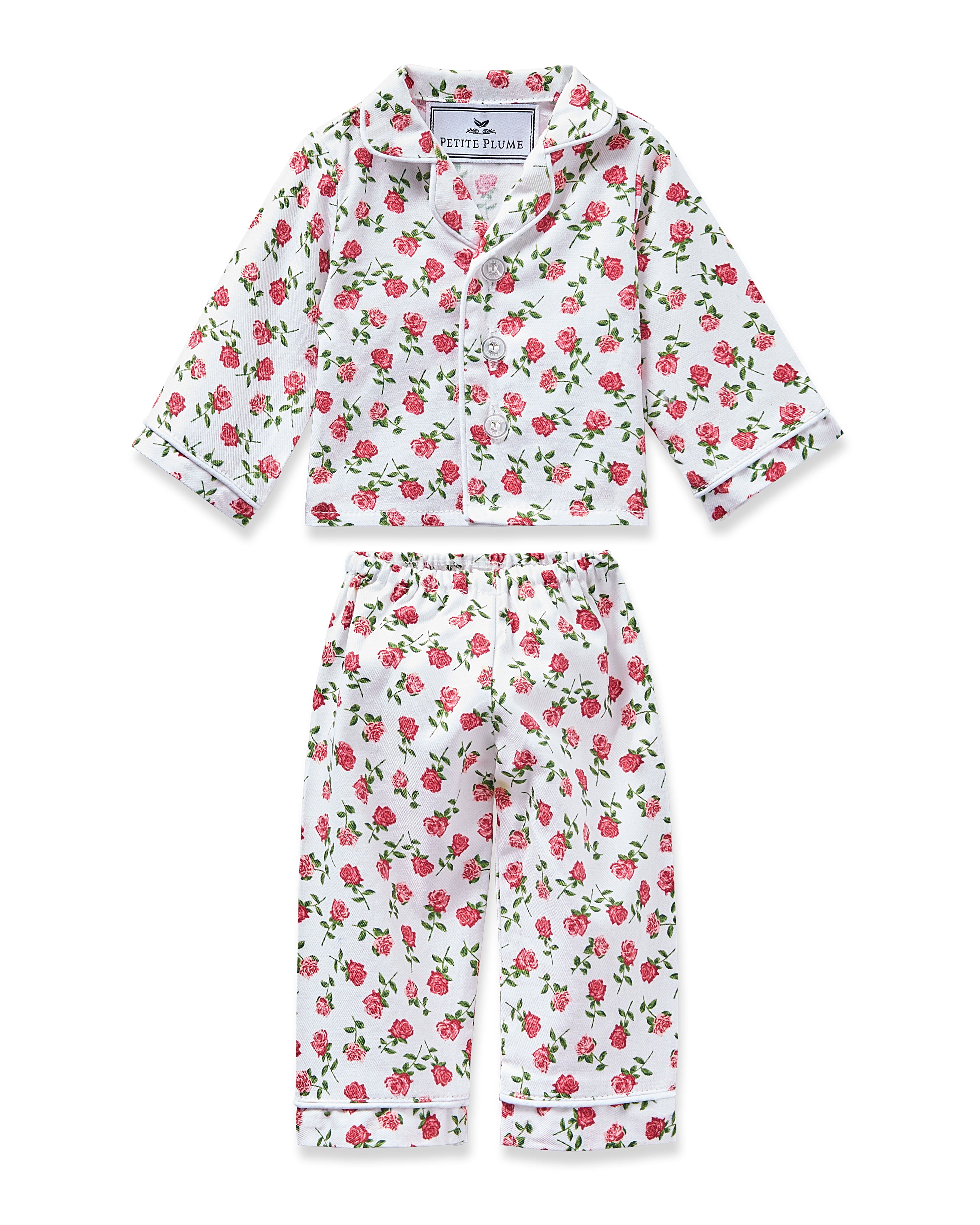 The Doll Twill Pajama Set in Petite Petals by Petite Plume features a floral design with pink roses and green leaves on white. It includes a long-sleeve button-up top and matching pants, offered in sizes for children and an 18 doll for charming twin moments.