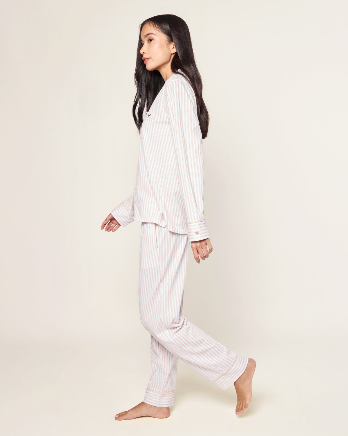 The Women's Pima Pajama Set in Camel Ticking with "Thankful" embroidery features a beige and white striped, long-sleeve button-up top with a chest pocket and matching elastic-waist pants, shown neatly arranged on a white background.