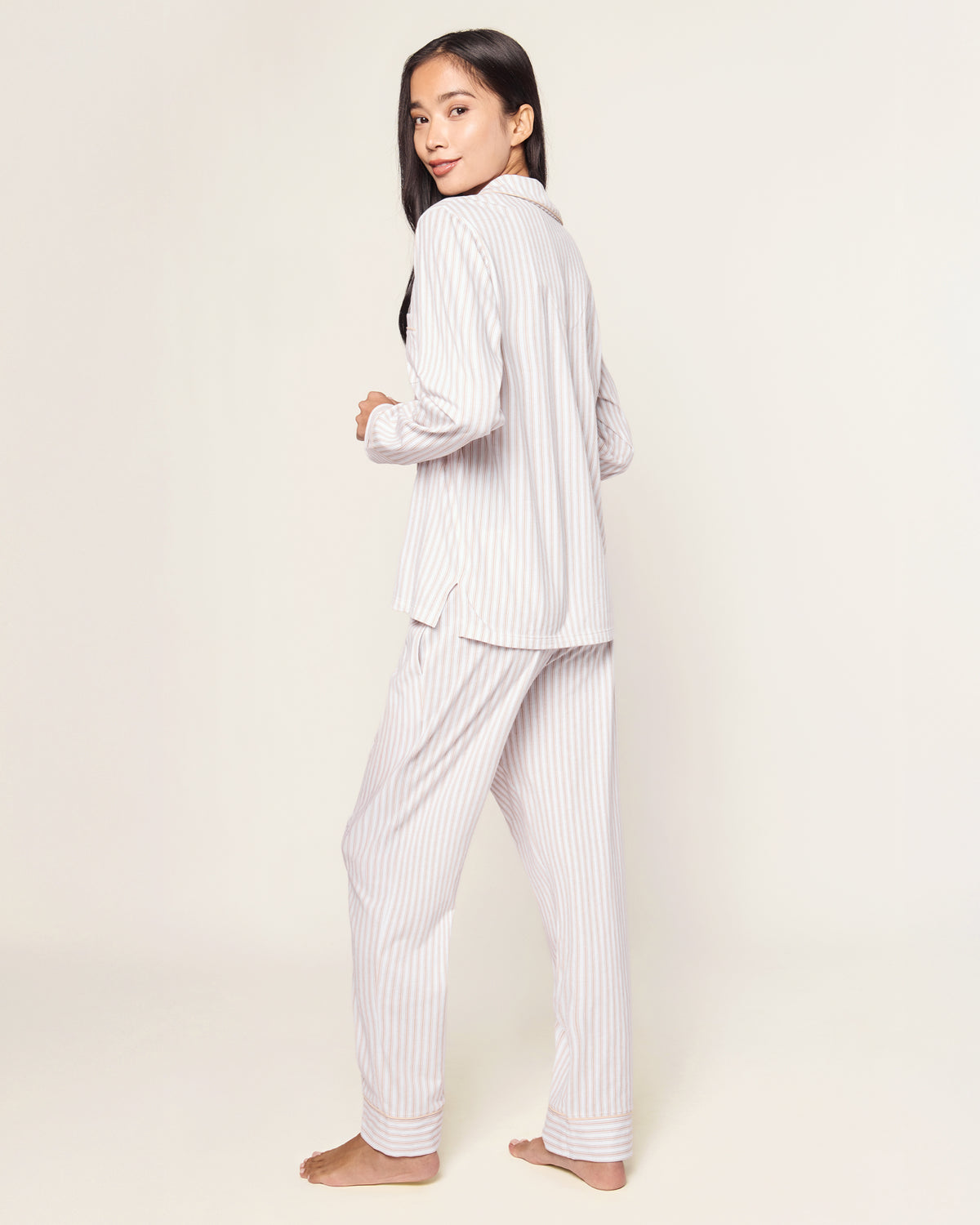 The Women's Pima Pajama Set in Camel Ticking with "Thankful" embroidery features a beige and white striped, long-sleeve button-up top with a chest pocket and matching elastic-waist pants, shown neatly arranged on a white background.
