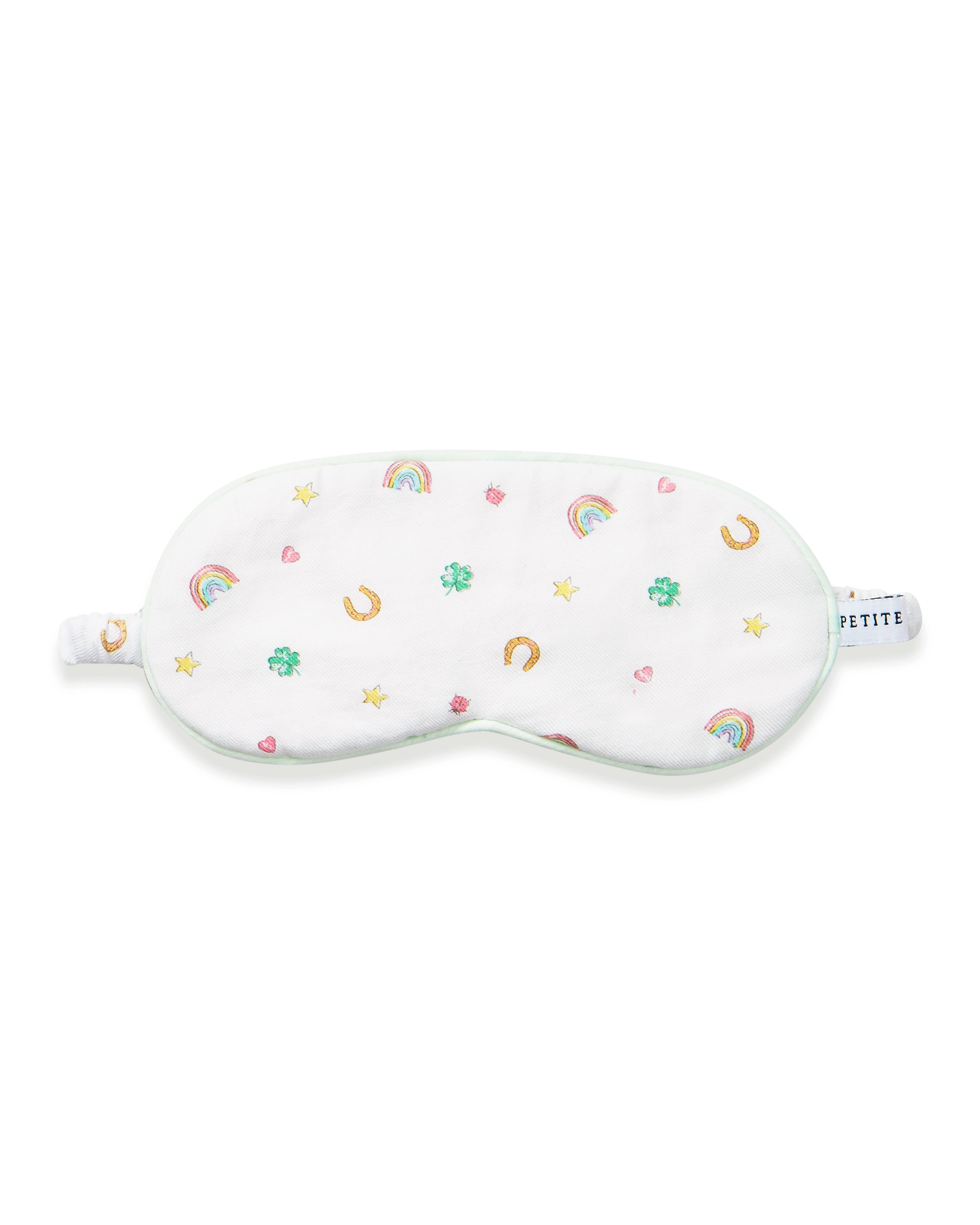 A young girl with long brown hair wears the Kid's Twill Sleep Mask in Good Luck Charms and a matching pajama top featuring rainbows, horseshoes, and clovers, standing against a neutral background.