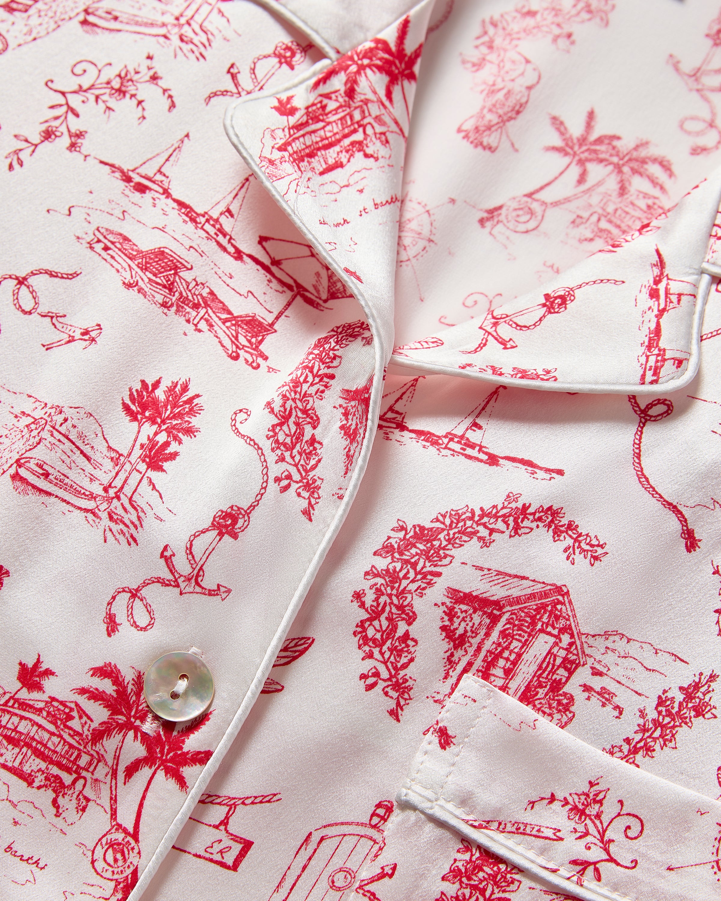 The Petite Plume x Eden Rock Reverie Women's Silk Pajama Set features a long-sleeve button-up top and pants with a white background and red toile print of scenic and animal motifs.